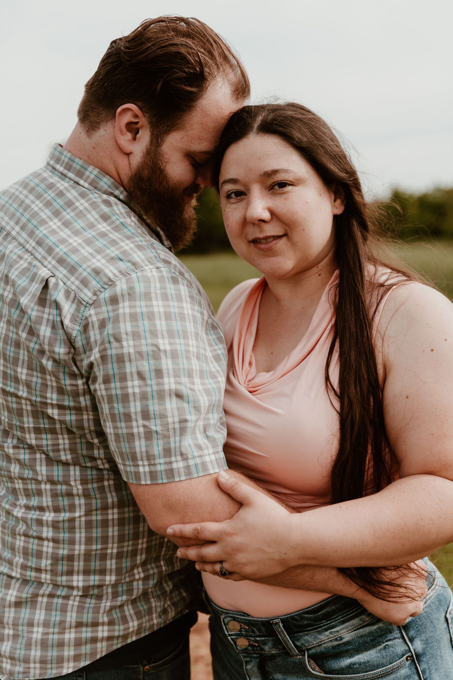 A couple sharing an intimate moment outdoors, with soft lighting and a natural background.