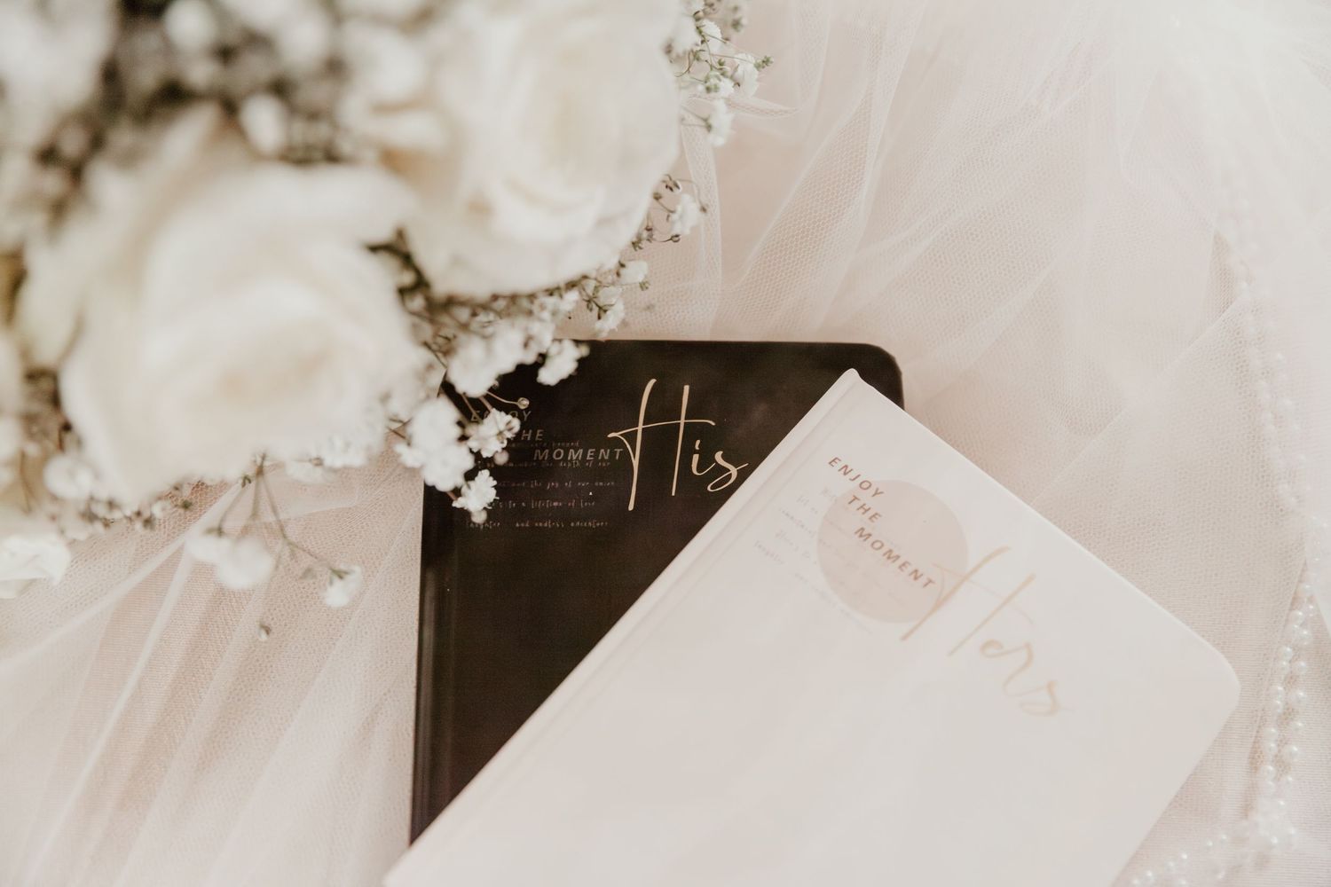 Wedding veil draped over black and white invitation cards with delicate floral accents and calligraphy.
