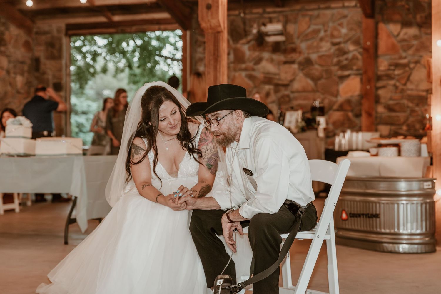 A tender moment shared between newlyweds at a rustic barn reception venue with stone walls and wooden barrels.