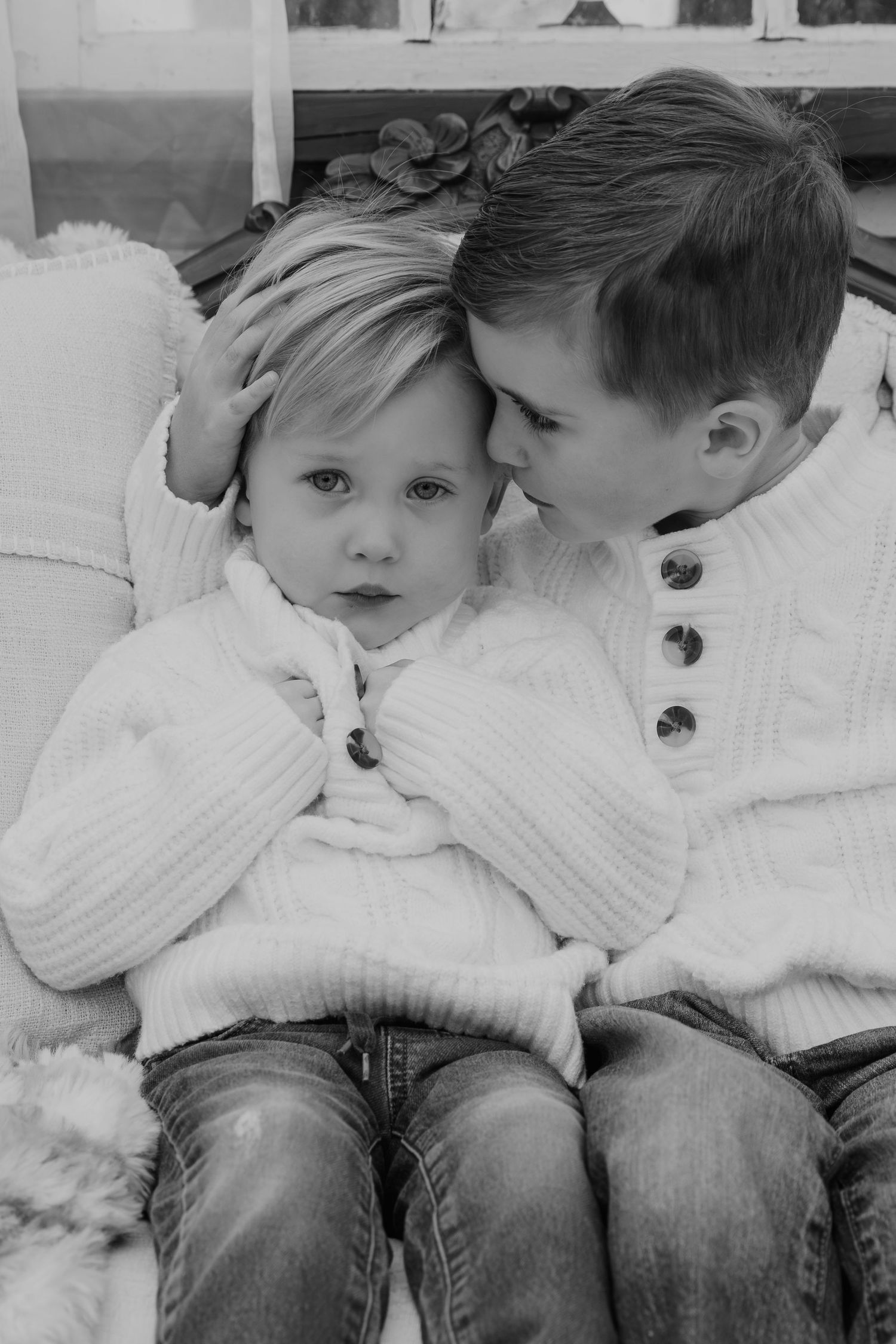 Black and white sequence showing two children in white sweaters sharing a sweet moment together.