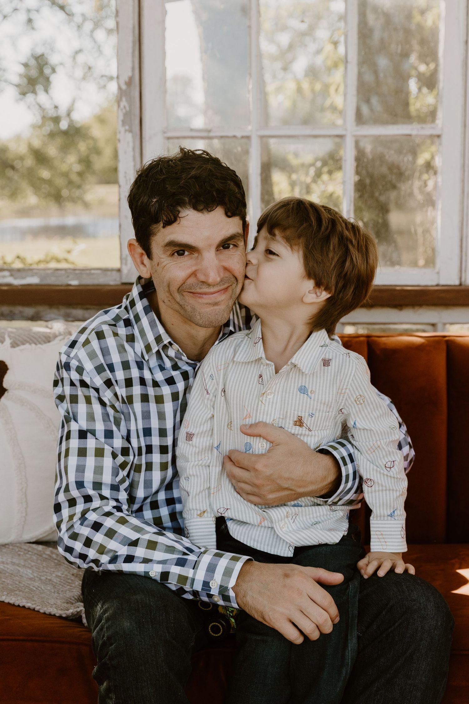 A sweet moment captured in a series of four candid photos showing affectionate interaction on a couch by a window.