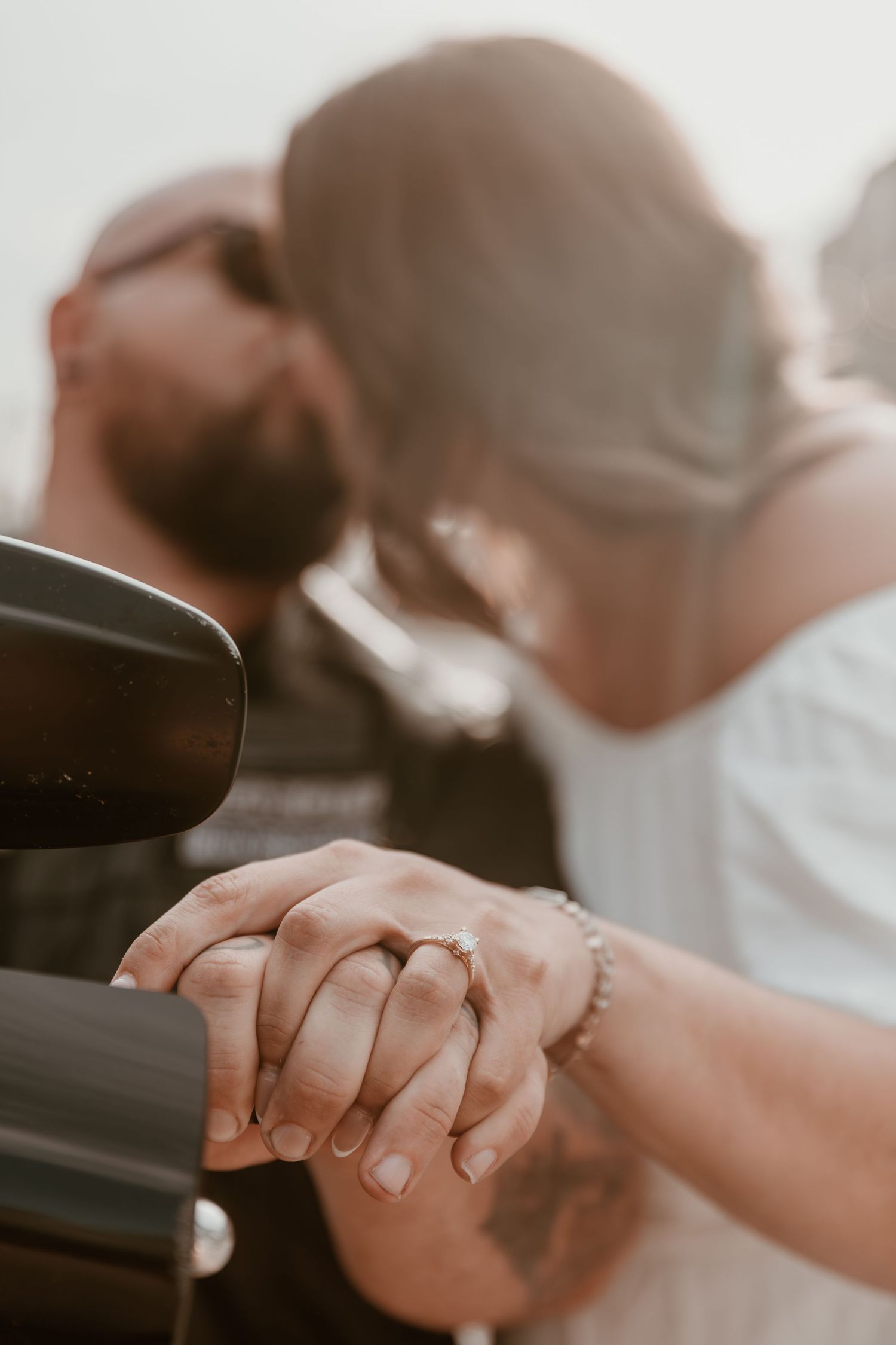 Close-up view of clasped hands with wedding rings in warm sunlight creating an intimate romantic moment.