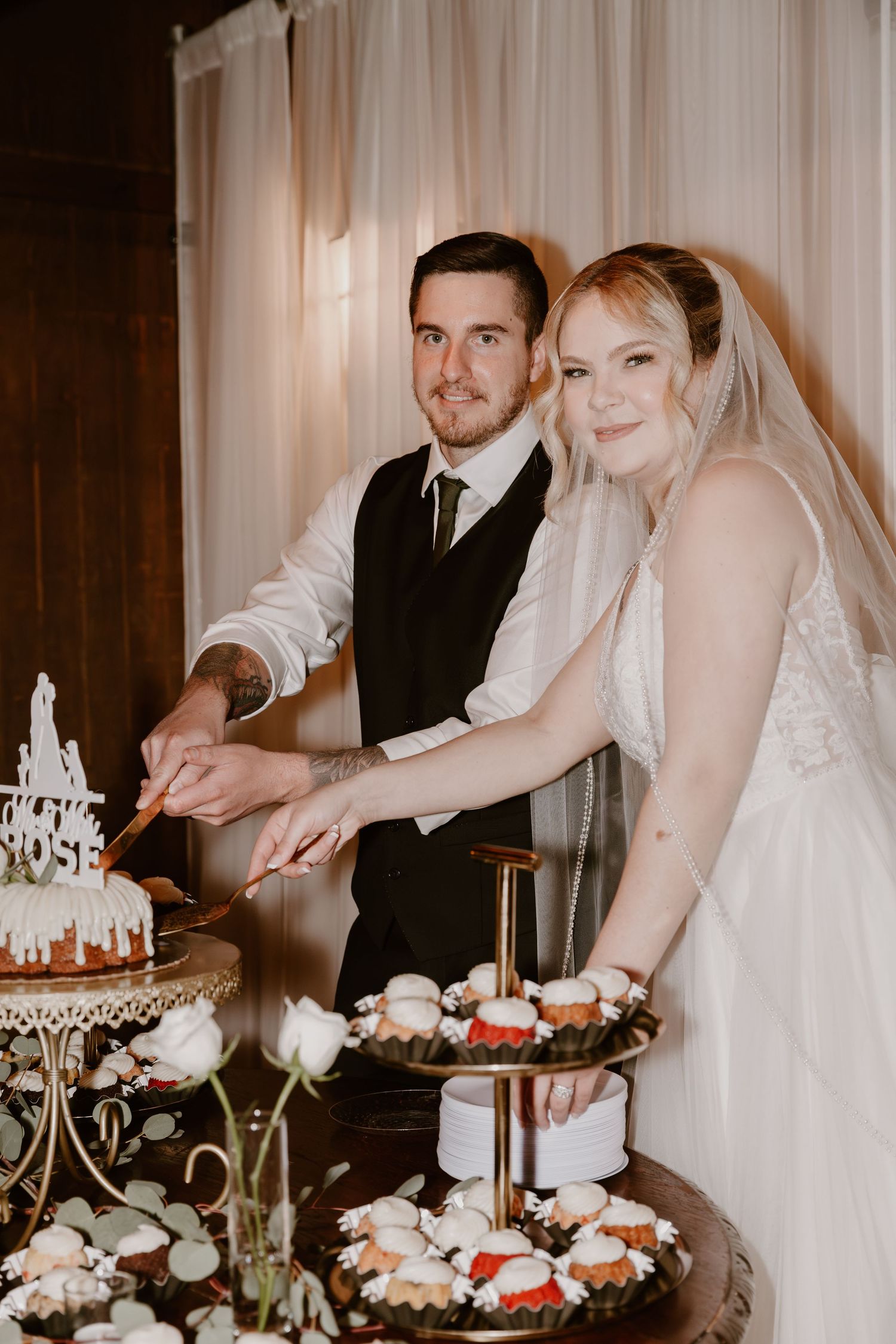 A newlywed couple cuts their wedding cake together at their reception.