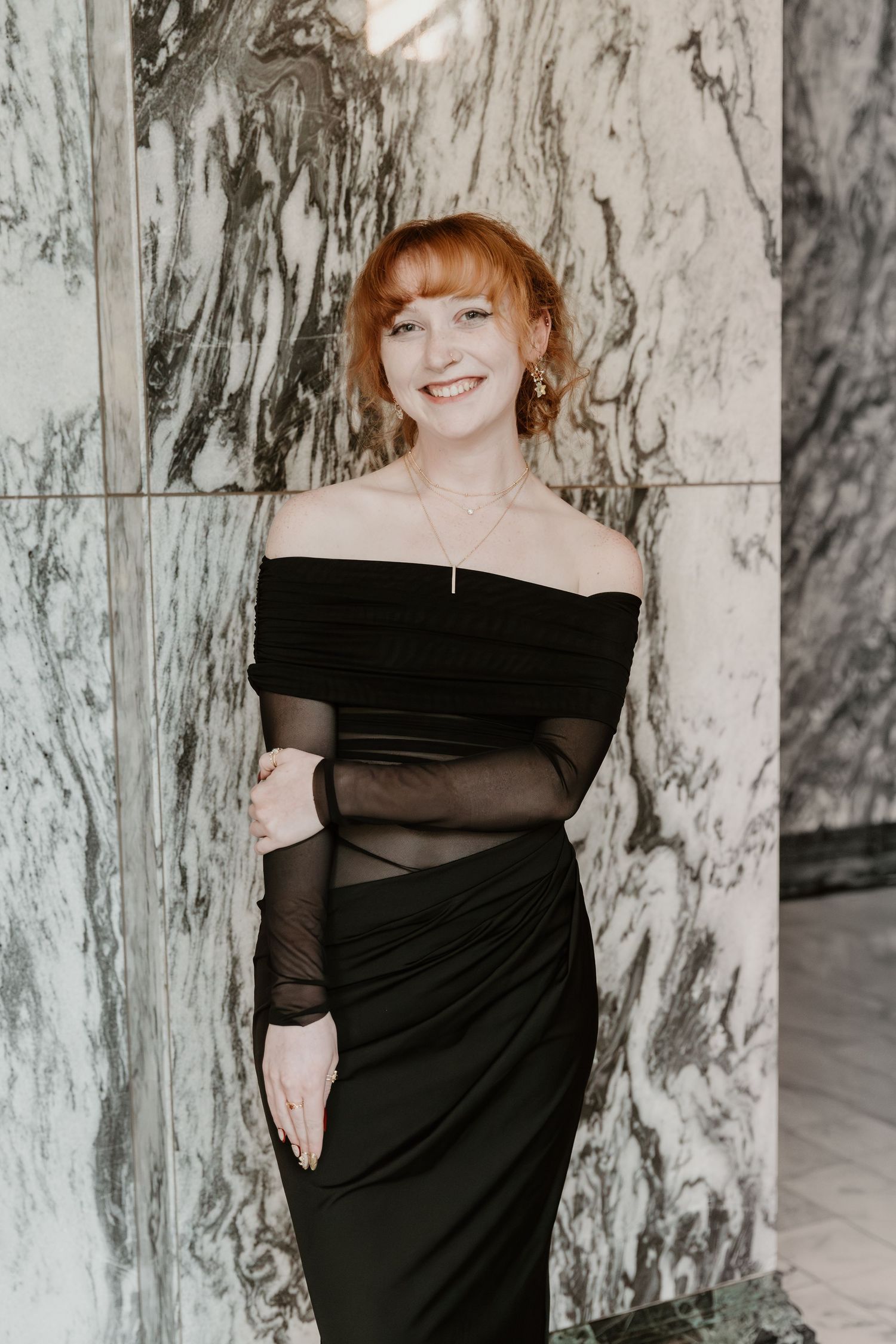 A series of four similar photos showing someone in a black off-shoulder dress against a marble-textured wall.