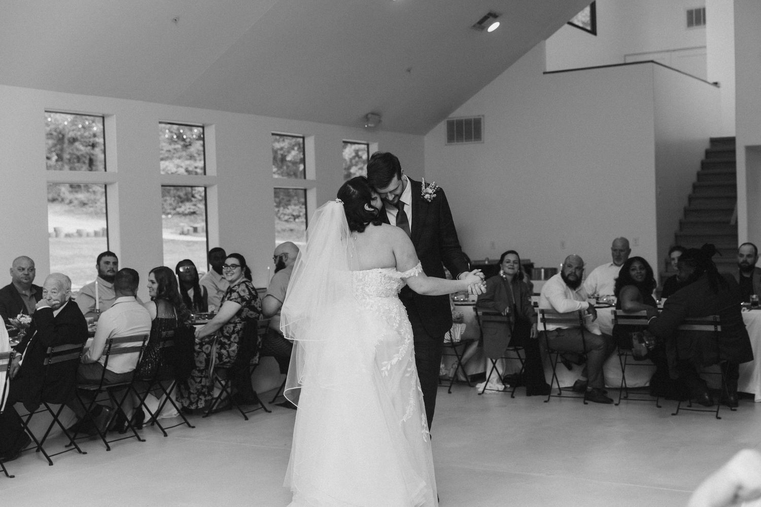 Bride and groom share their first dance at wedding reception while guests watch in elegant venue.