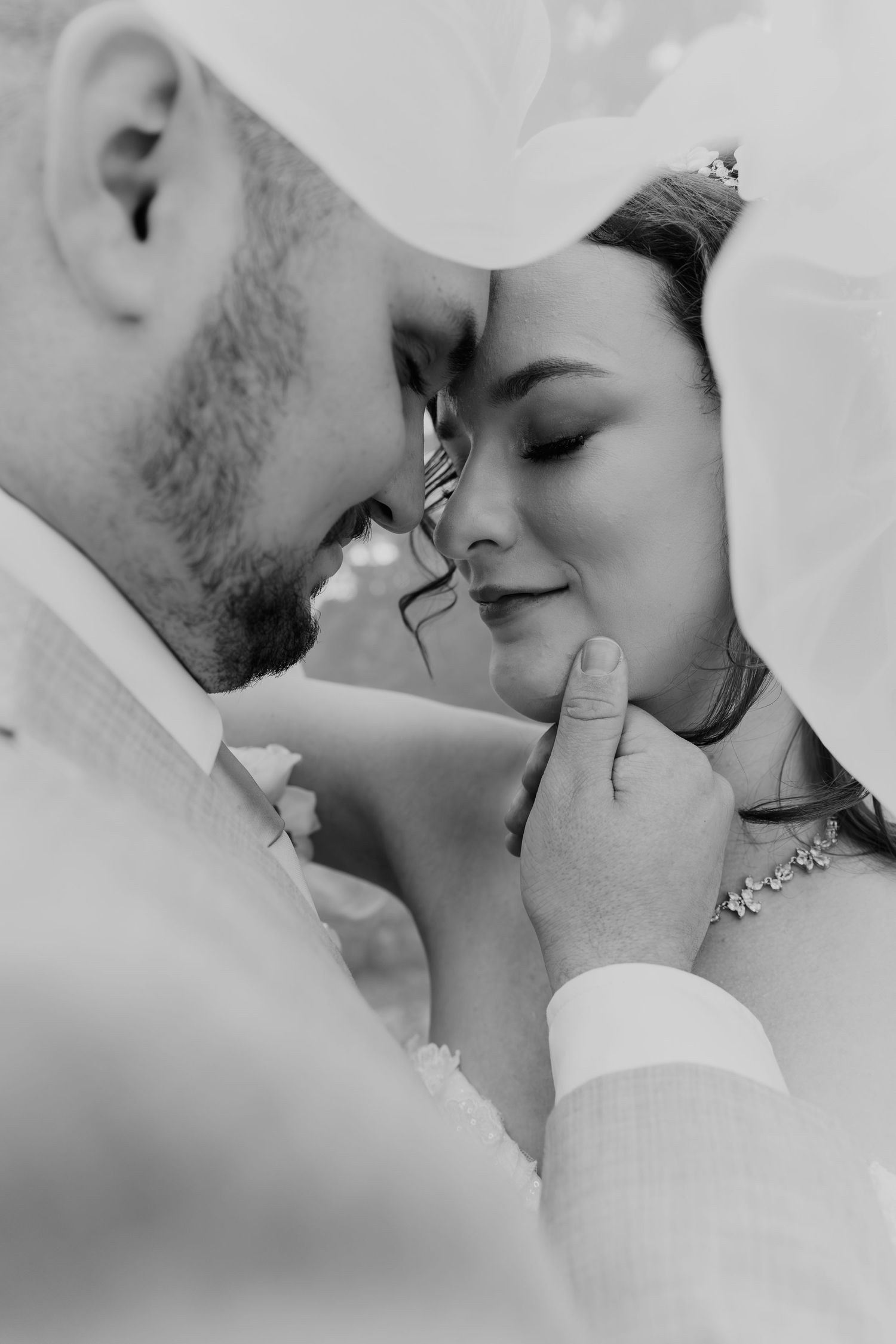 Black and white close up photo of a tender romantic moment between a couple with their faces close together.