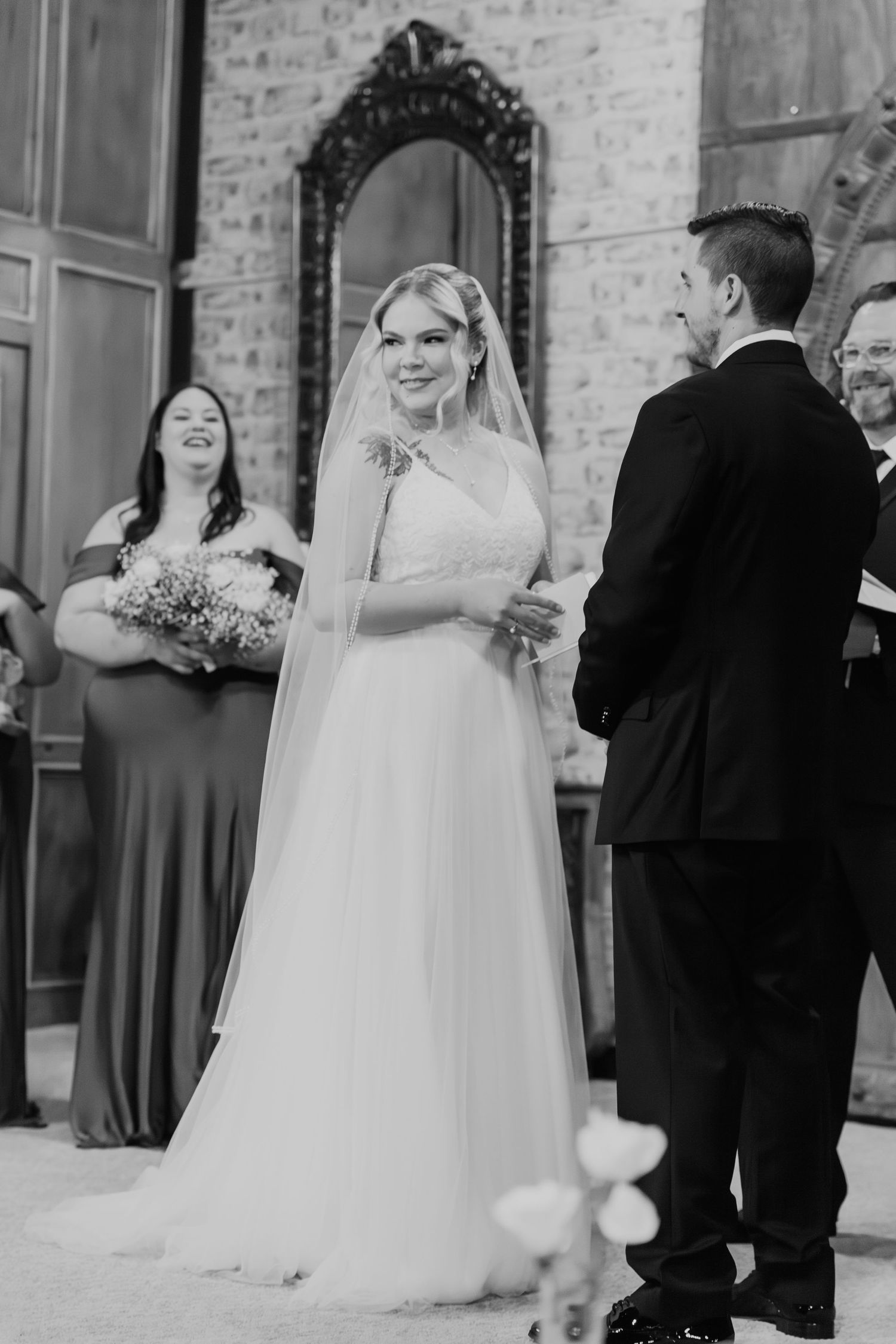 Black and white candid wedding ceremony photos showing moments between couples and guests in an indoor venue.