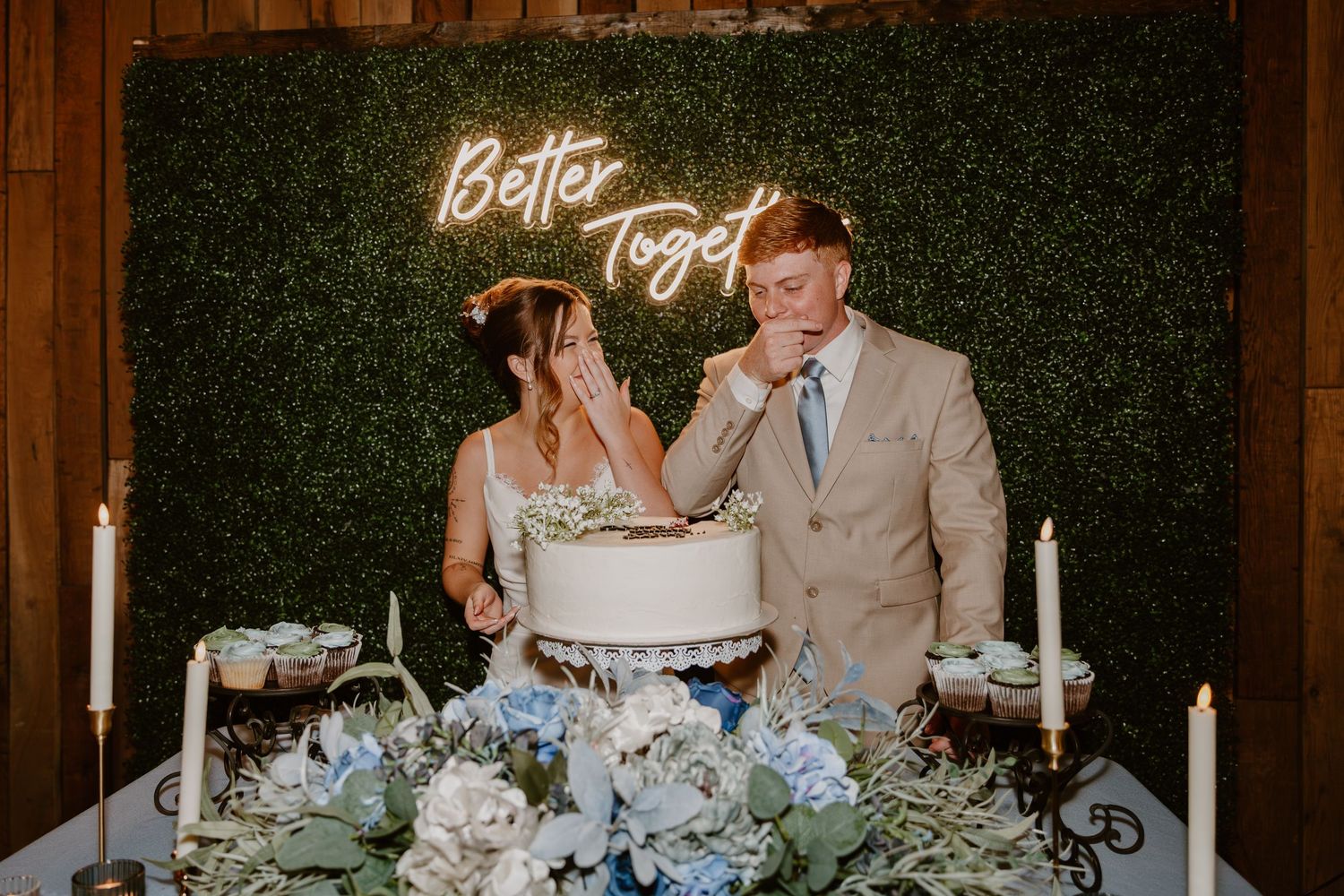 A modern rustic wedding reception table decorated with greenery and elegant place settings.