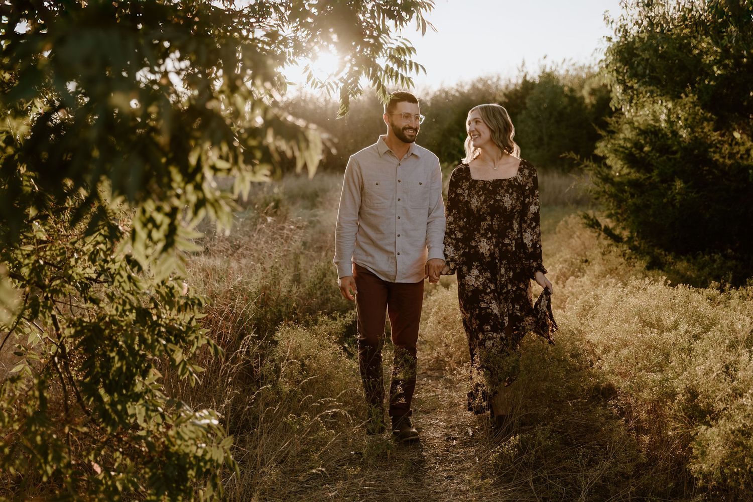 Silhouetted figures walking together on a sunlit nature path during golden hour.