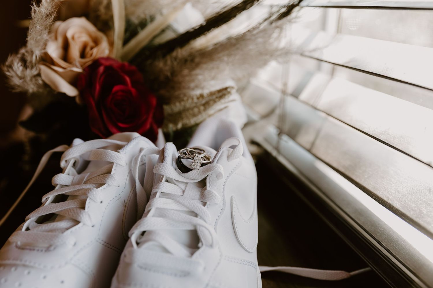 White ballet shoes with satin ribbons lay gracefully arranged on a wooden surface in natural lighting.