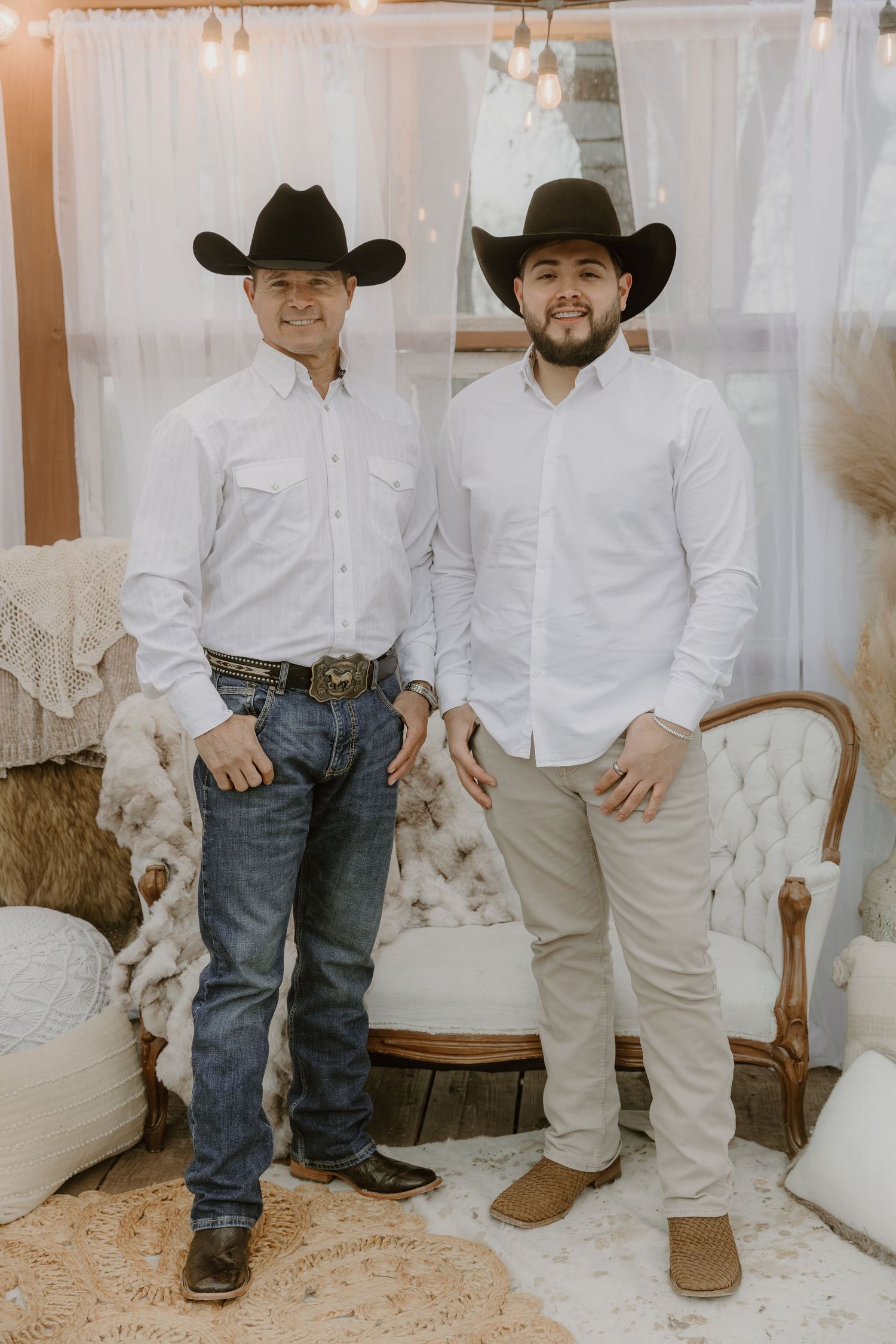 Close-up view of people wearing cowboy boots, white shirts and jeans standing together in a rustic setting.