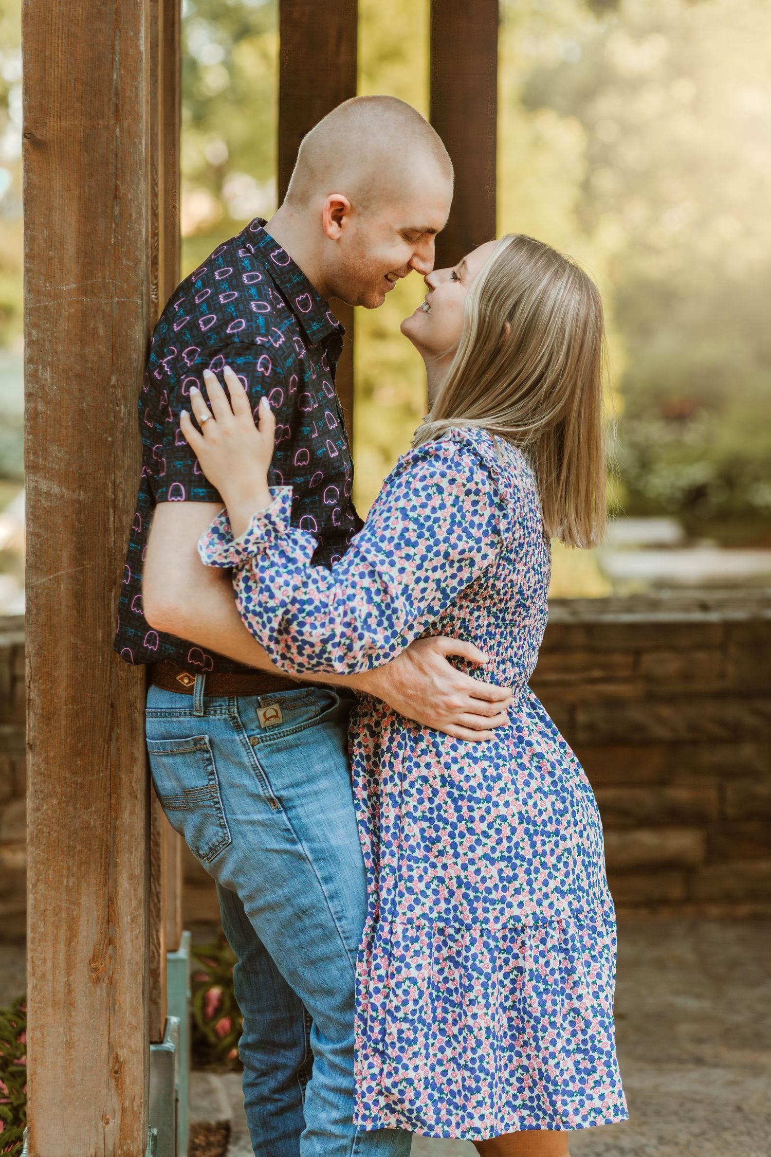 Intimate moment between couple in floral prints standing in wooden gazebo.
