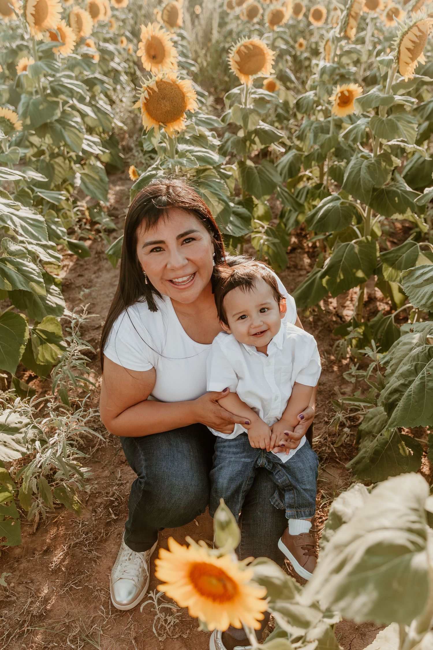 Joyful moment captured in a sunflower field during golden hour with warm lighting and blooming yellow flowers.