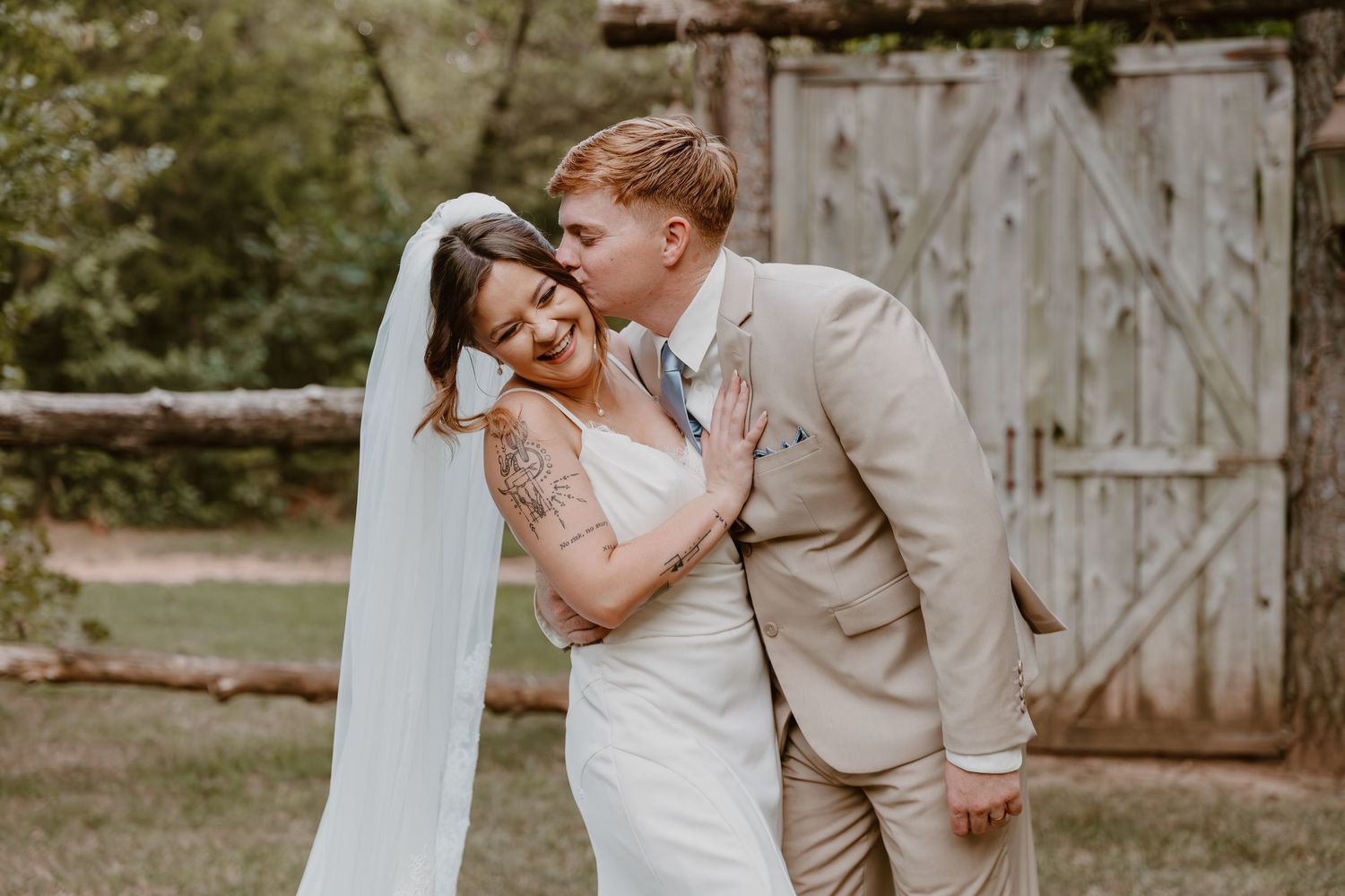 The bride and groom share intimate moments against a rustic wooden backdrop during their romantic wedding photoshoot.