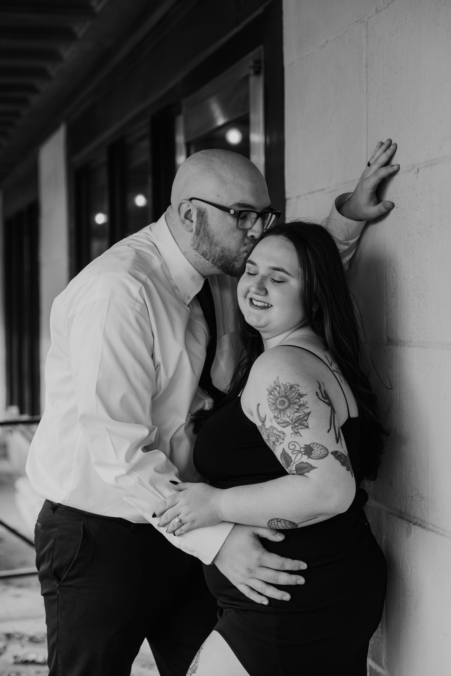 A romantic black and white photo sequence showing a couple embracing against a wall in four progressive shots.