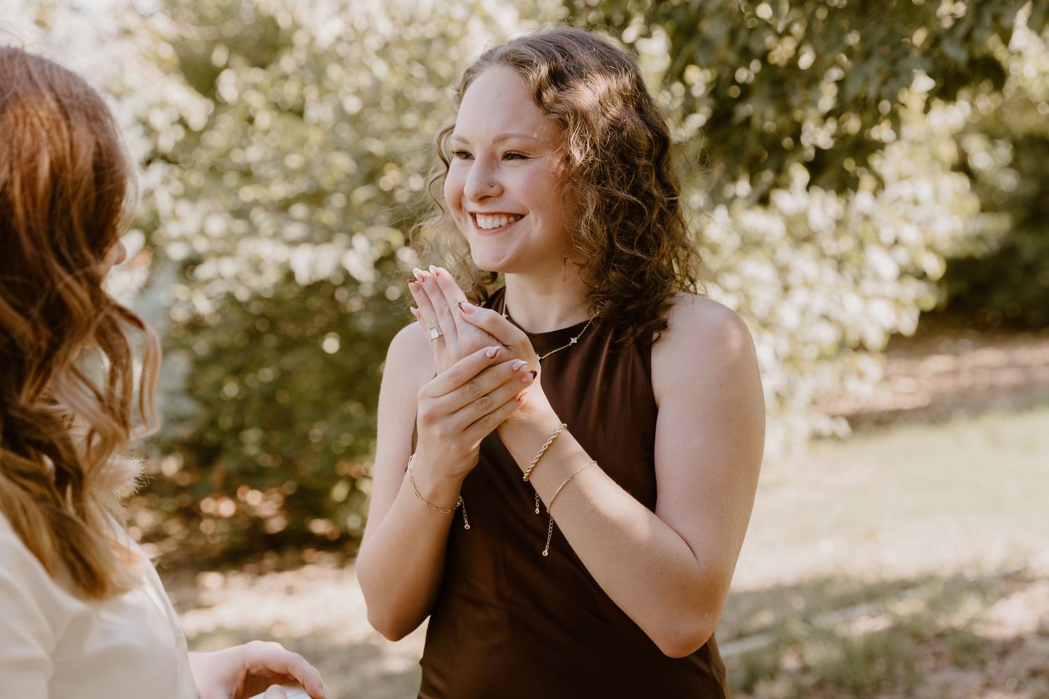 A person in a brown dress reacts with excitement during an emotional outdoor moment.