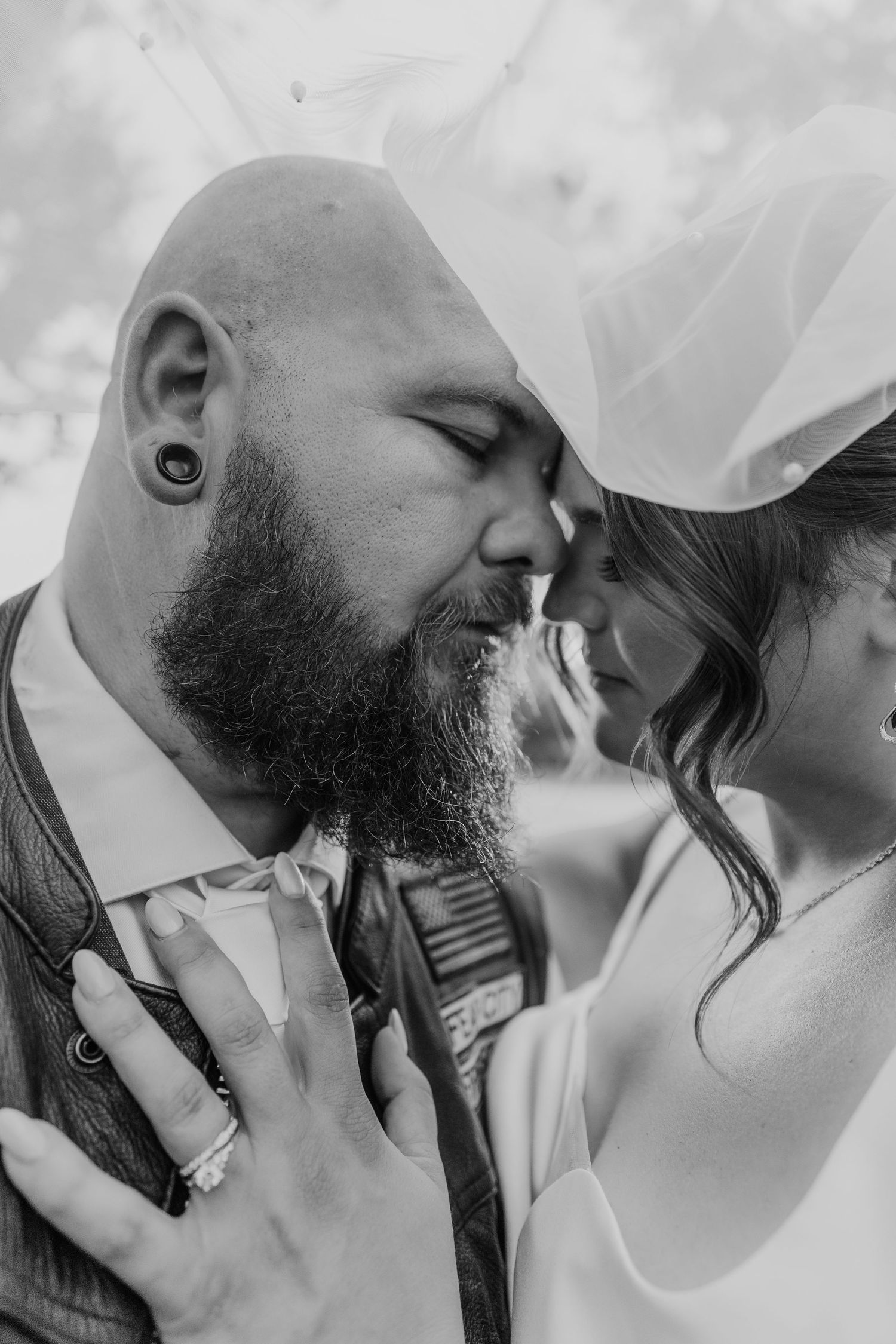 A tender black and white wedding photo showing an intimate close up moment between a bearded groom and bride.