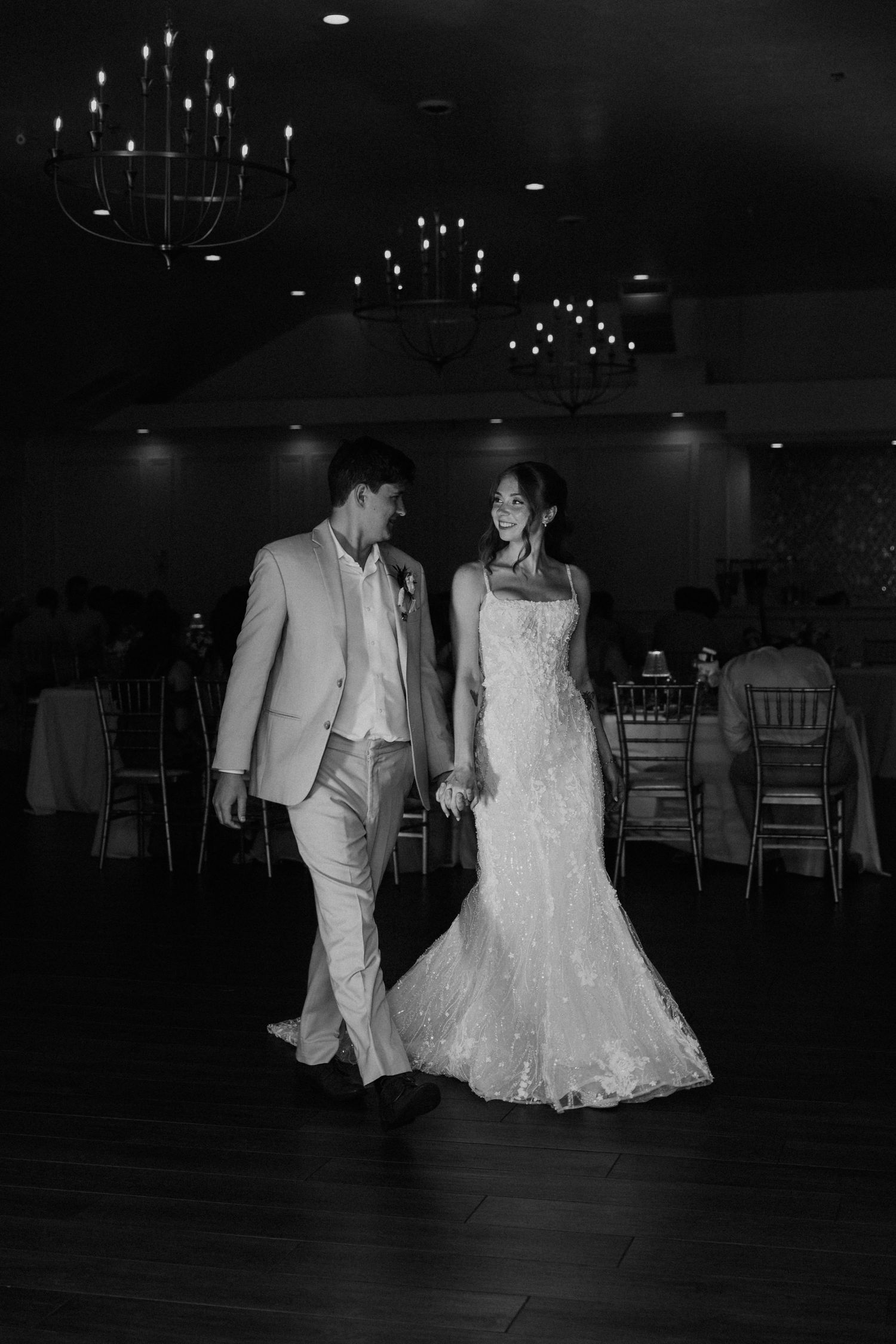 Black and white photo of bride and groom sharing first dance at elegant wedding reception venue.