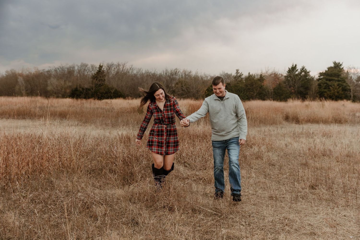 A couple walks hand in hand through a golden autumn field during sunset creating a romantic silhouette.