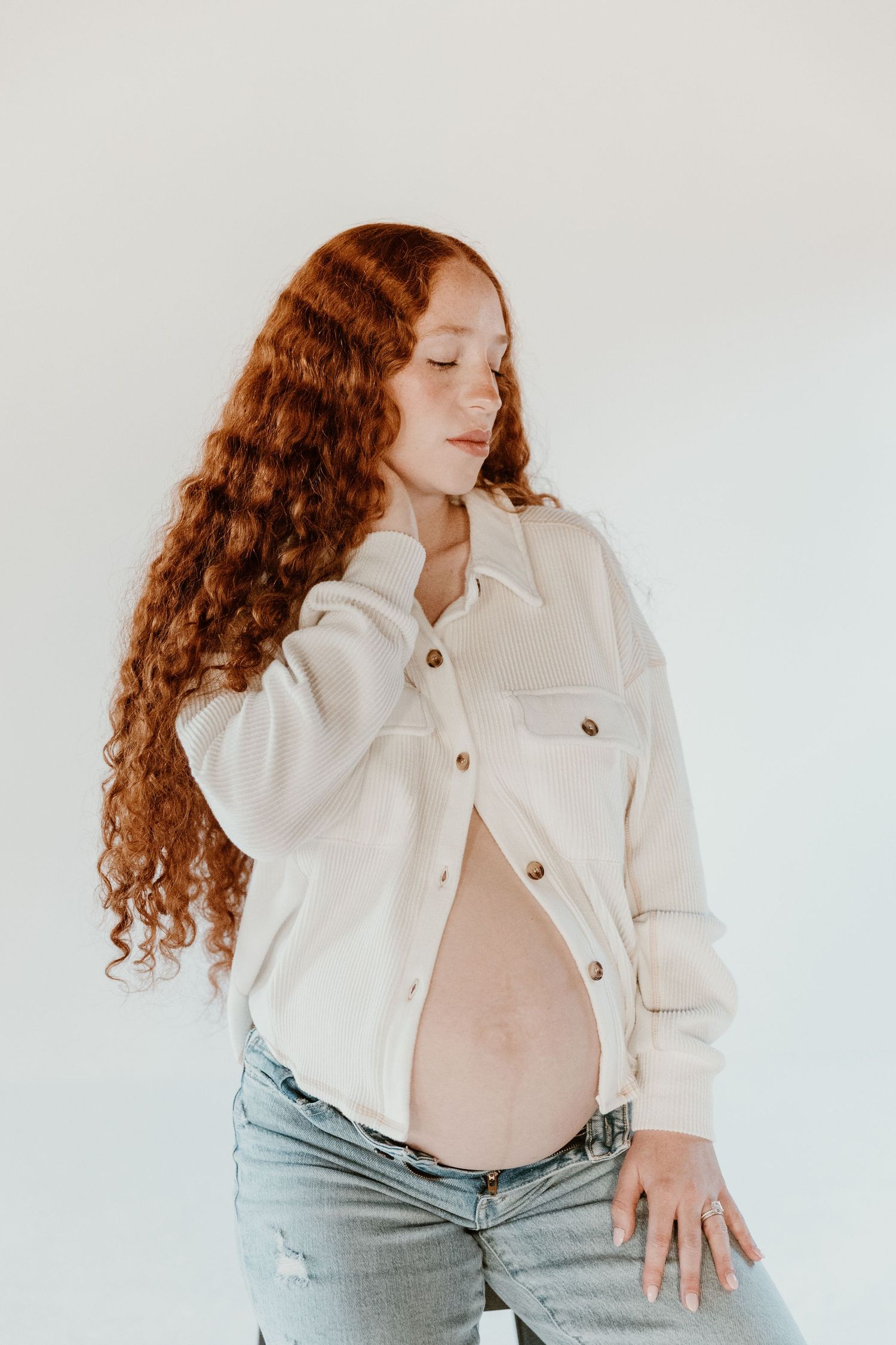 Four artistic fashion photos showing a model with flowing red curls wearing a white denim jacket and light jeans.