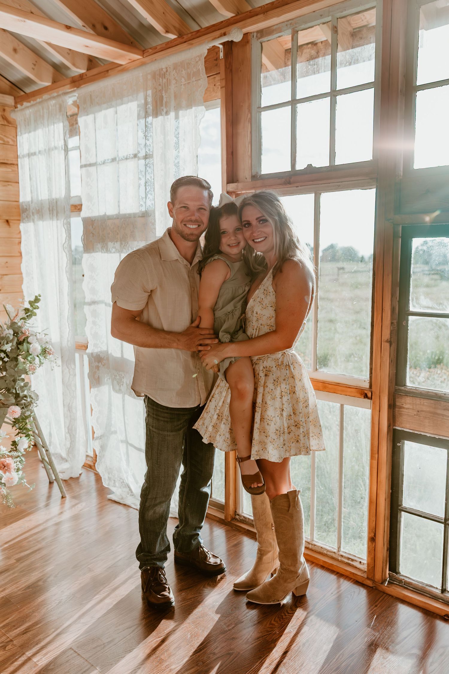 Couple dancing together in a rustic wooden sunroom with large windows and warm lighting.