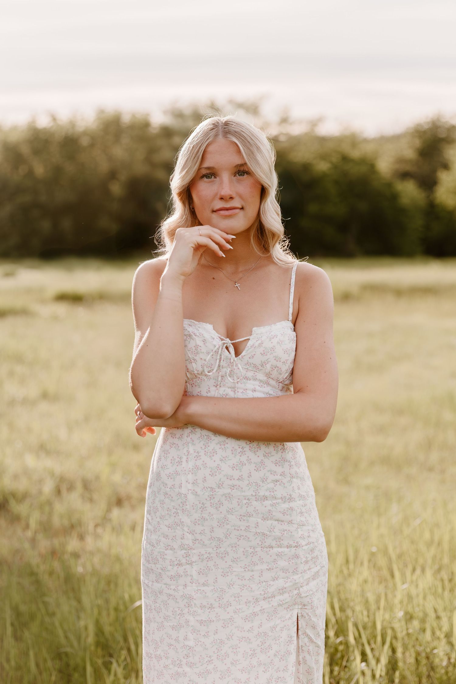 Elegant white lace dress with spaghetti straps photographed in a golden meadow during sunset.