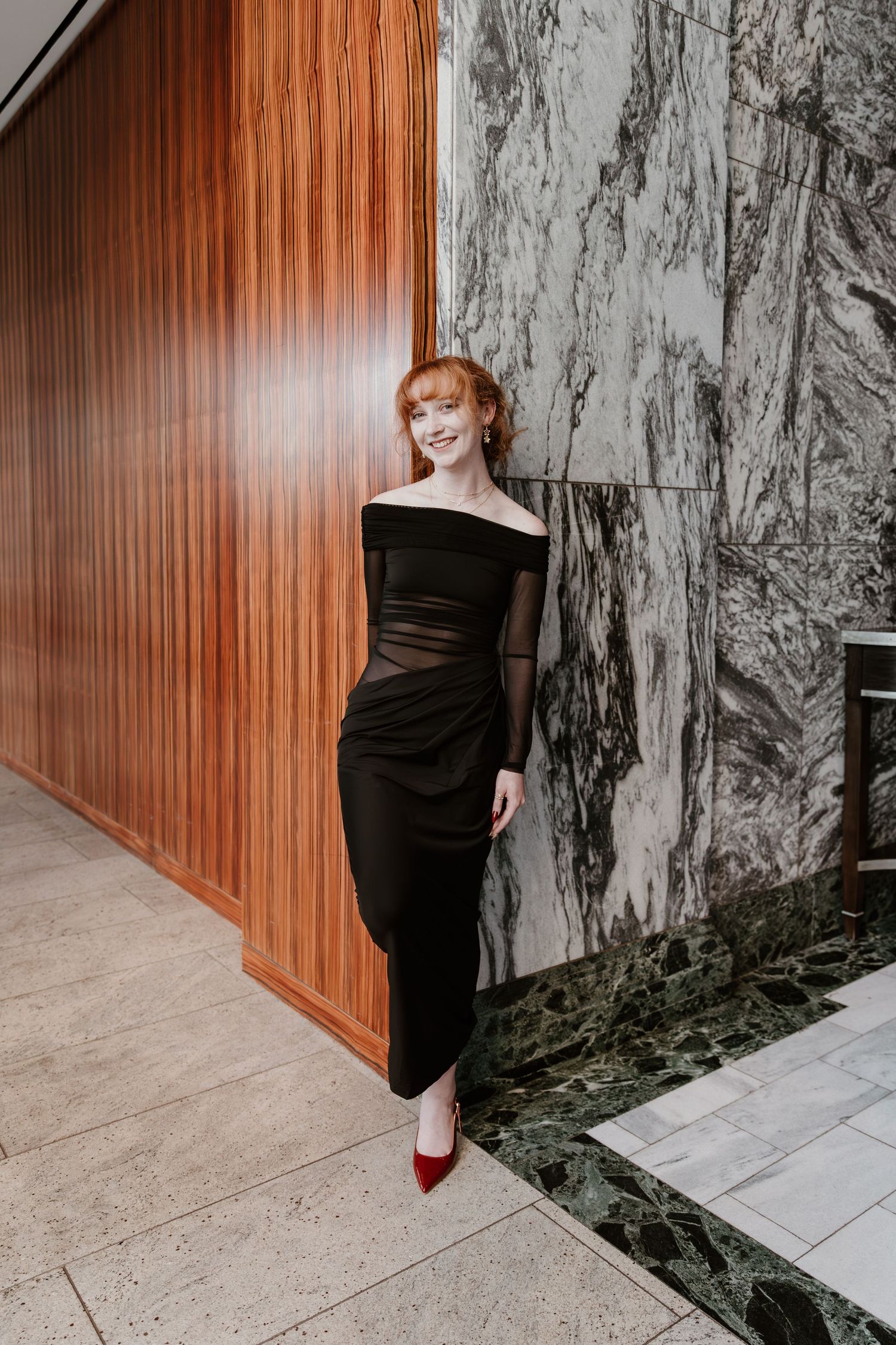 A person in black attire stands against a modern interior with wood paneling and marble walls in a sequence of photos.