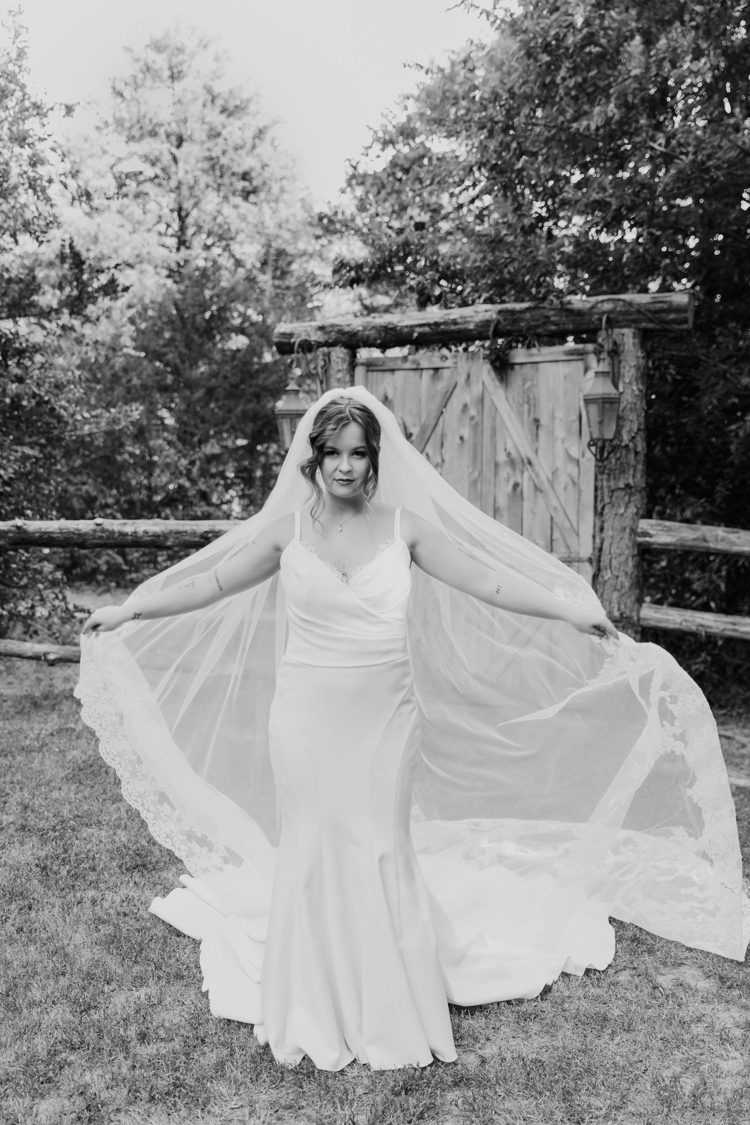 A flowing white wedding dress swirls gracefully in a black and white outdoor portrait.