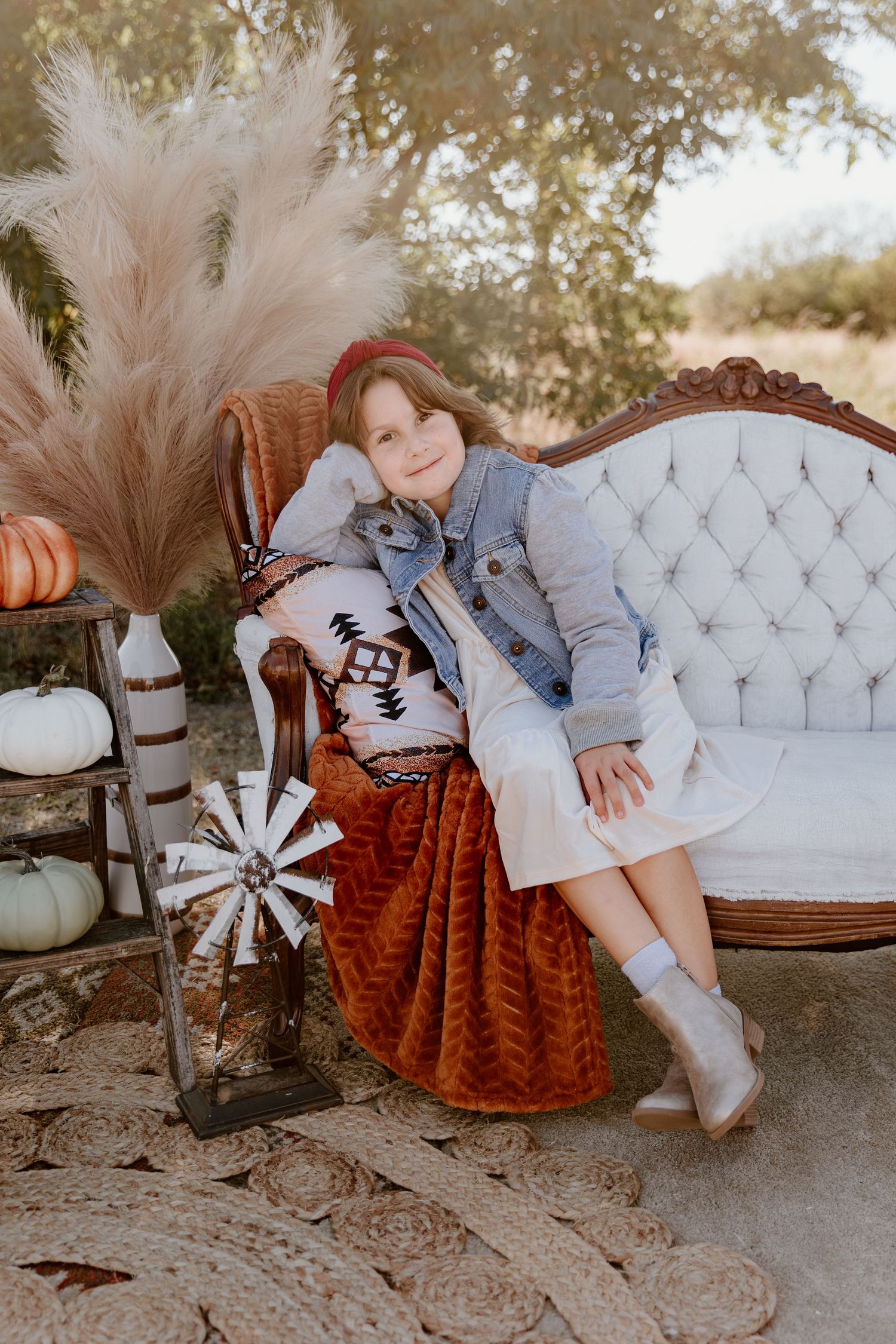 Rustic outdoor scene with vintage tufted loveseat, pampas grass decor, and western-inspired styling elements.