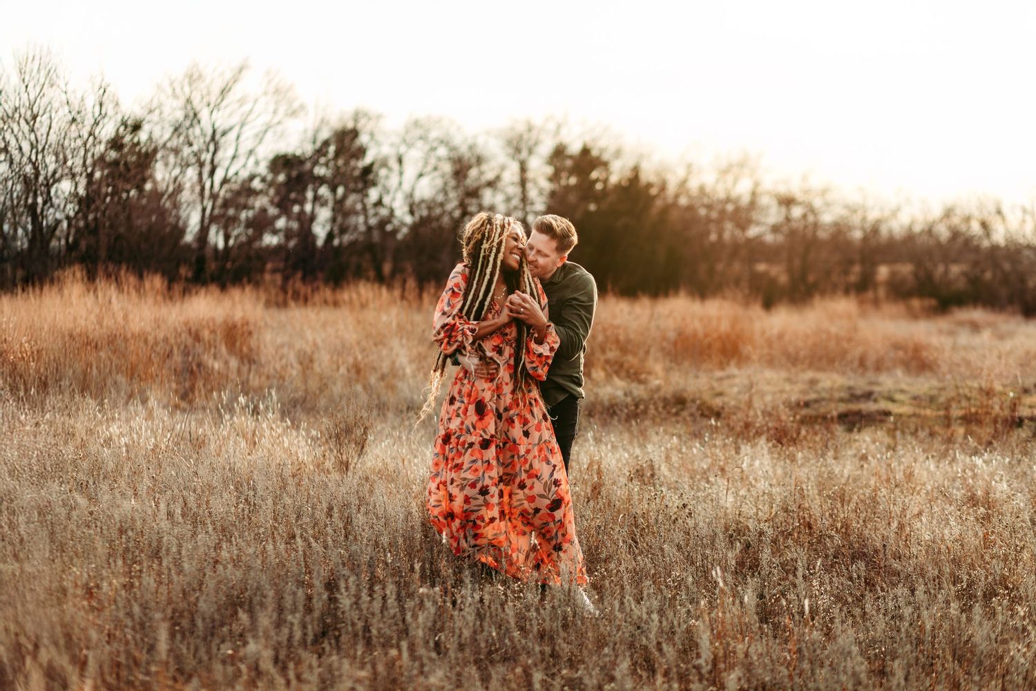 A romantic embrace in a field of tall grass during golden hour.