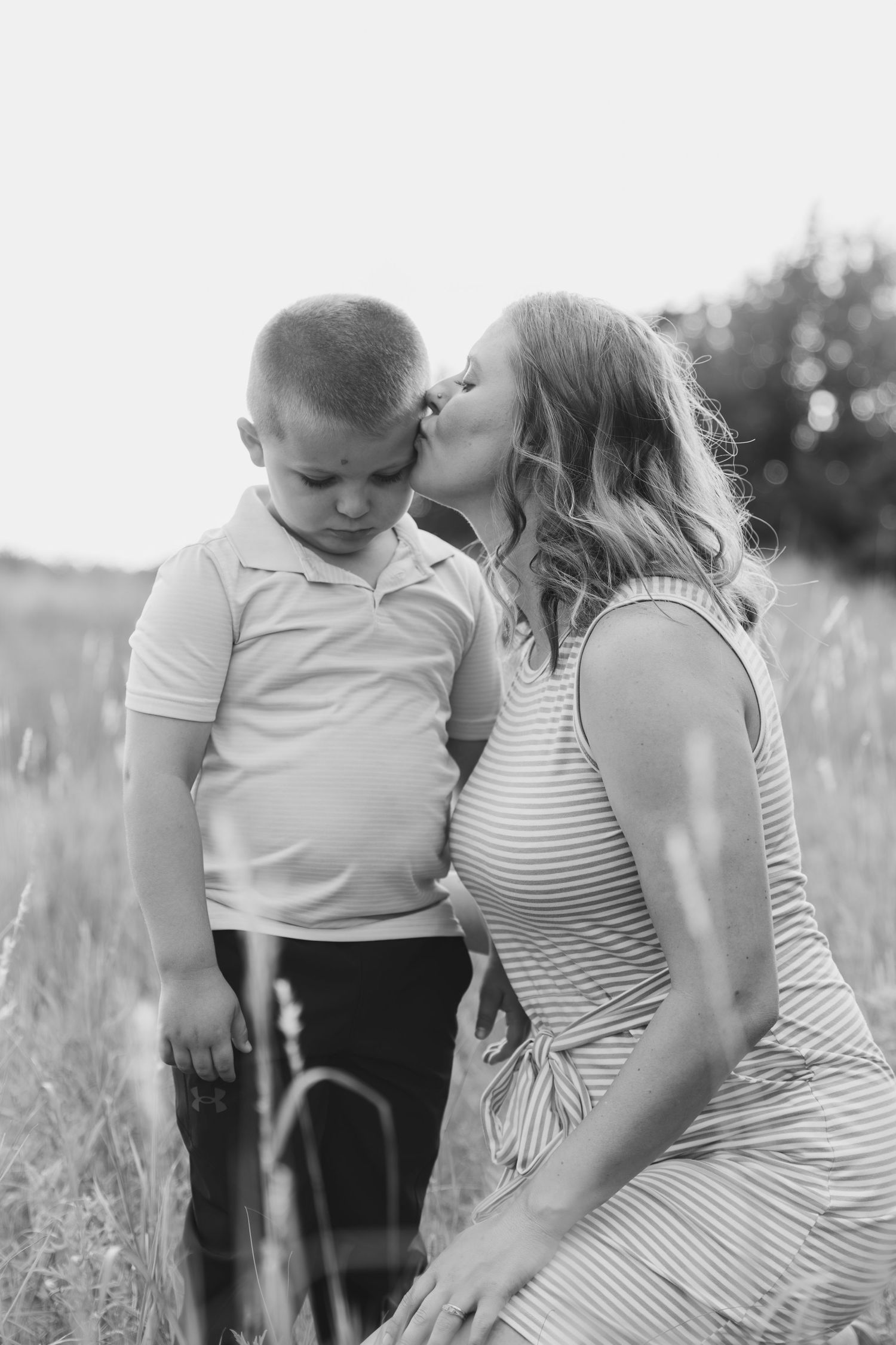 Sweet tender moment between mother and child in a sunlit grassy field.
