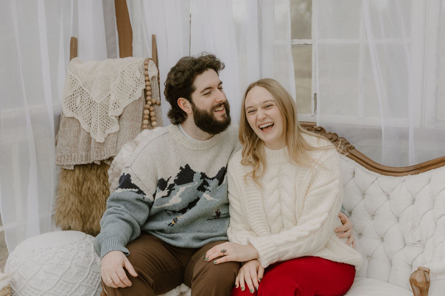 A couple sits together on a couch sharing a romantic moment in a cozy living room setting.