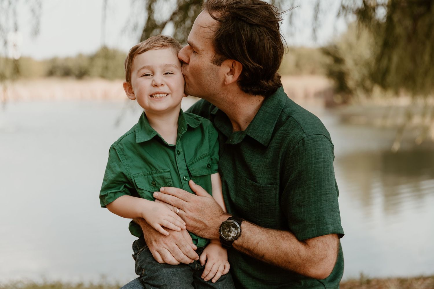 A tender family moment captured by a lake with warm natural lighting and joyful expressions.
