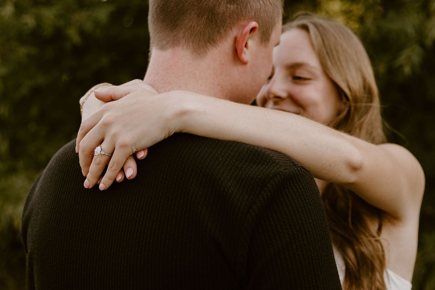 A couple embraces in a tender romantic moment against a blurred natural background.