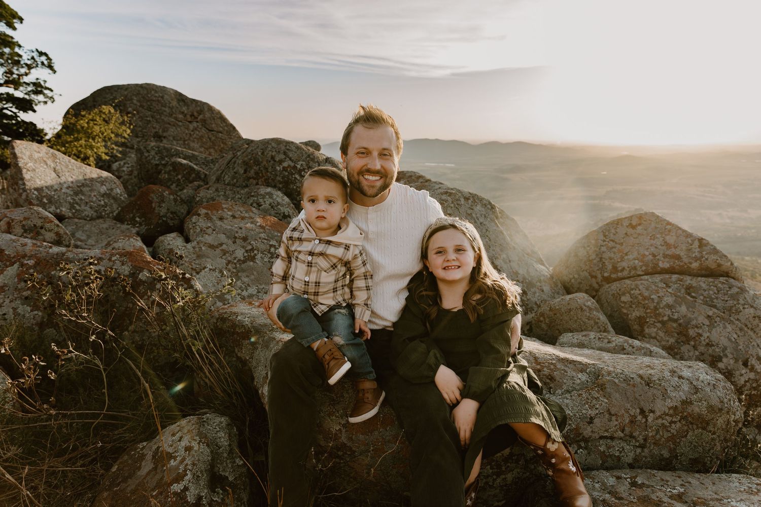 A family enjoying a sunset moment together on rocky terrain during a golden hour photoshoot.