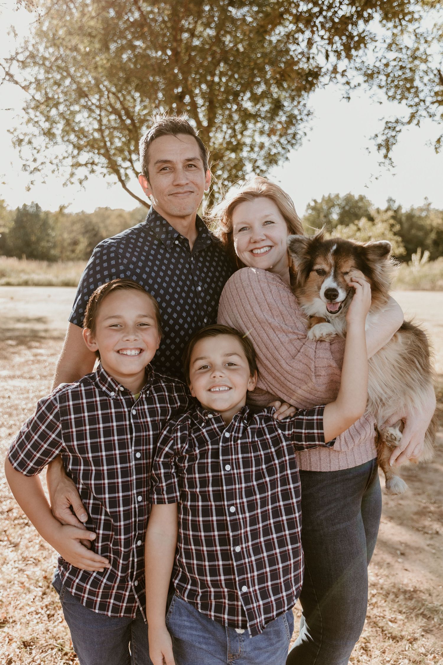 A family poses together outdoors with their small dog in a series of candid portrait photos at sunset.