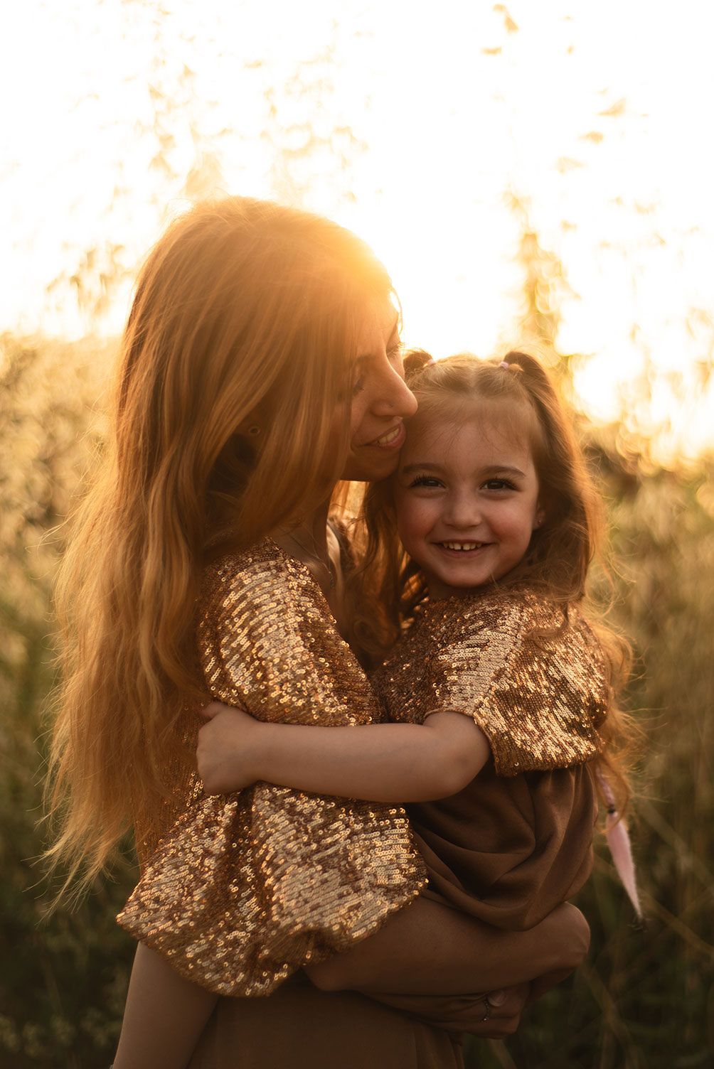 A warm sunset photo shows a joyful embrace between two people in a golden-lit field.