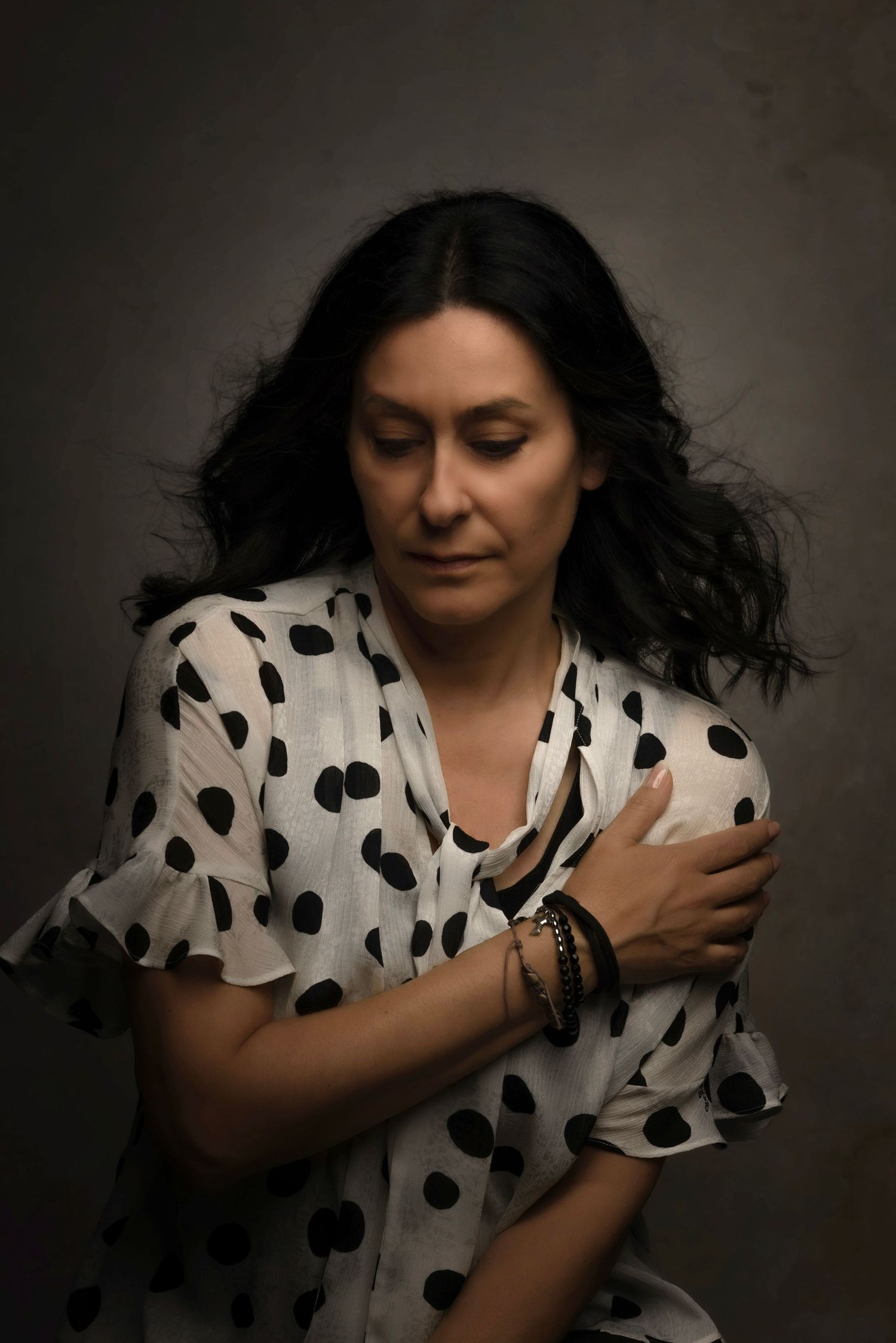 A series of artistic portraits showing a person in a polka dot dress making expressive movements against a dark background.
