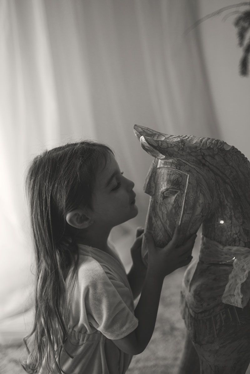 A series of black and white photos showing a person kissing a horse's nose in a tender moment.