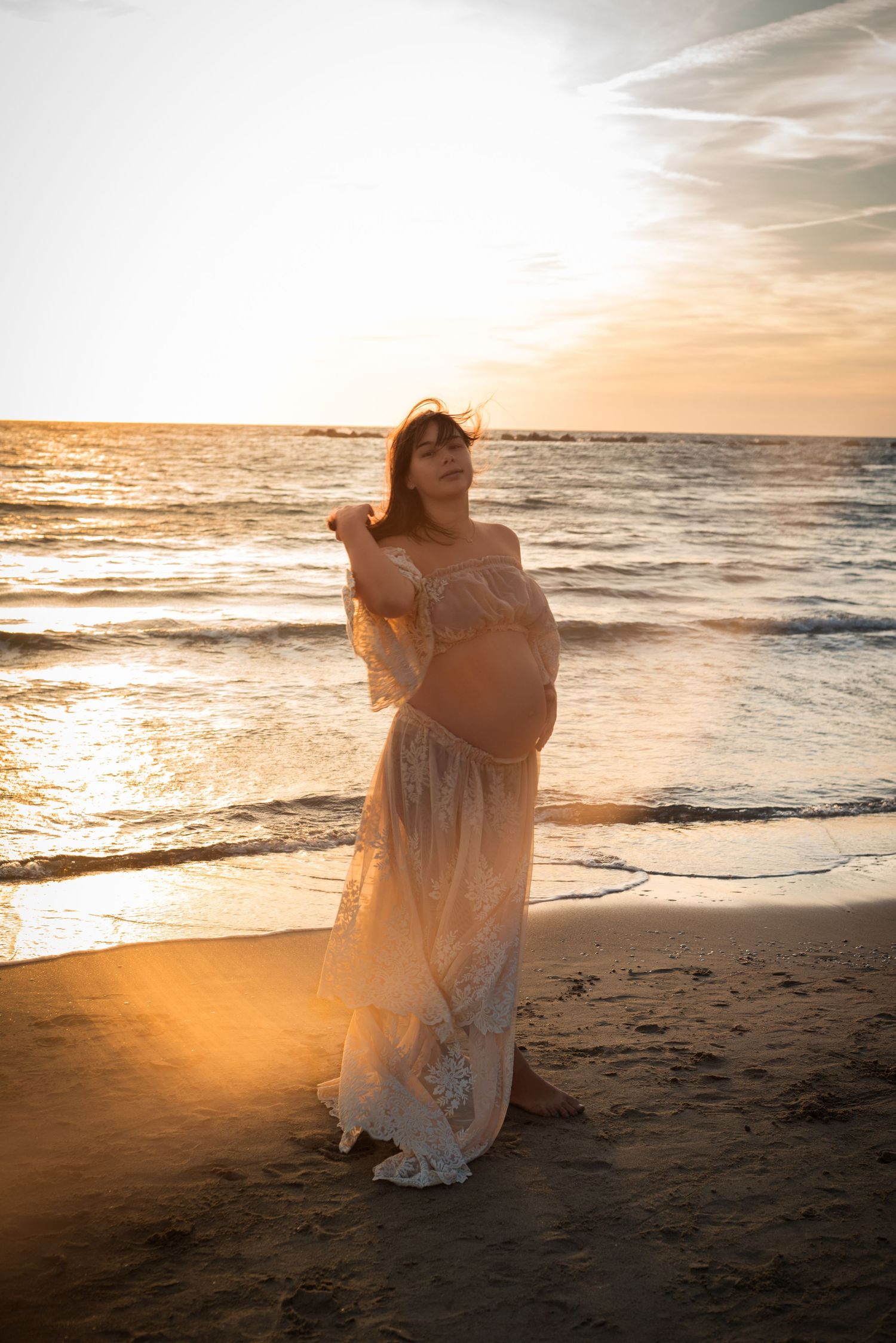 A figure in a flowing white dress dances gracefully along the beach at sunset creating a dreamy silhouette.