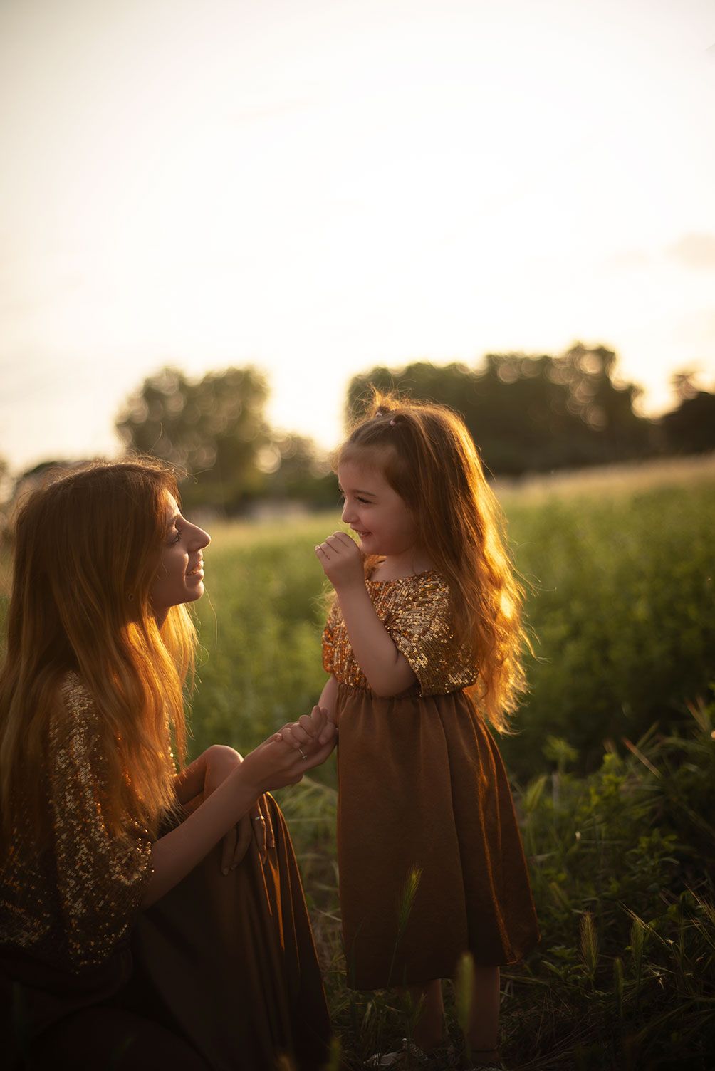 Two friends share a joyful moment in a sunlit meadow during golden hour as sunlight illuminates their hair.
