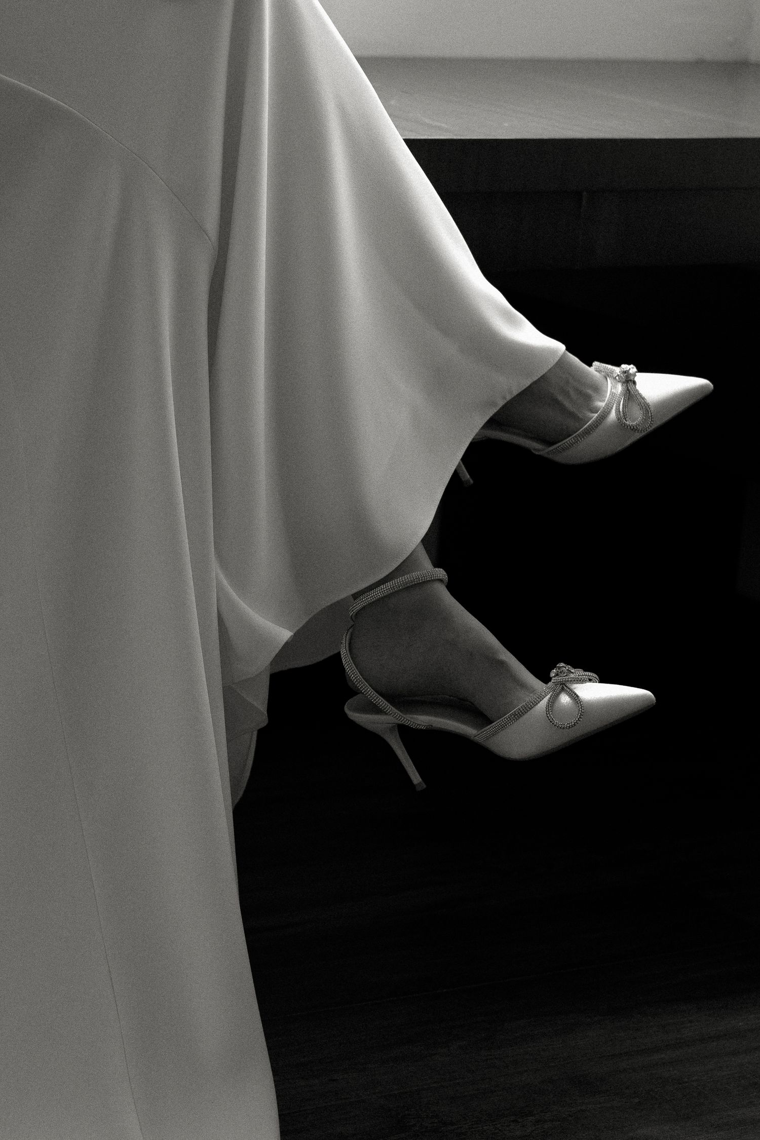 A series of black and white photographs showing elegant white ballet shoes against a dark background.