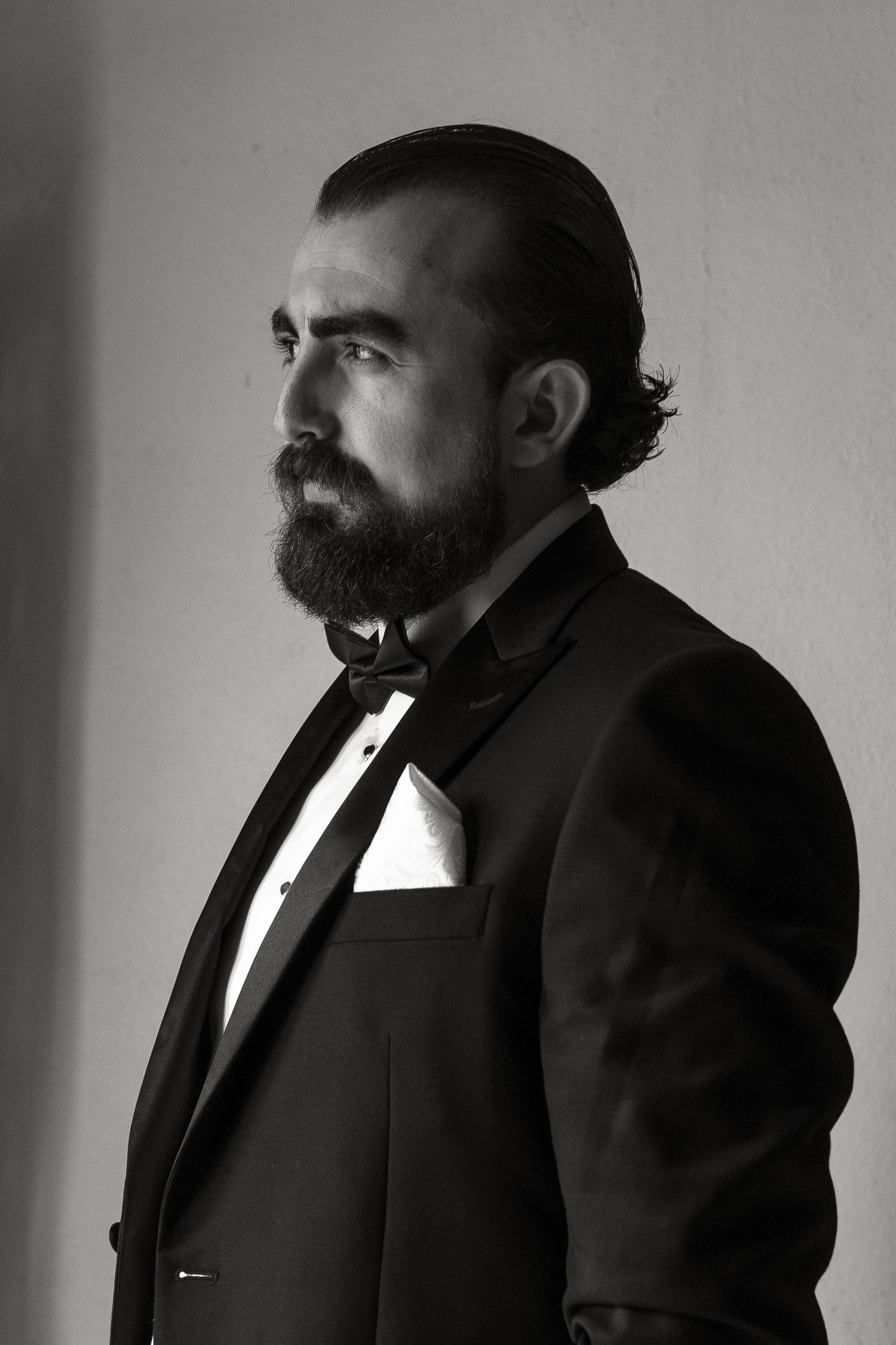Black and white portrait series showing a bearded figure in dark formal attire against a light background.