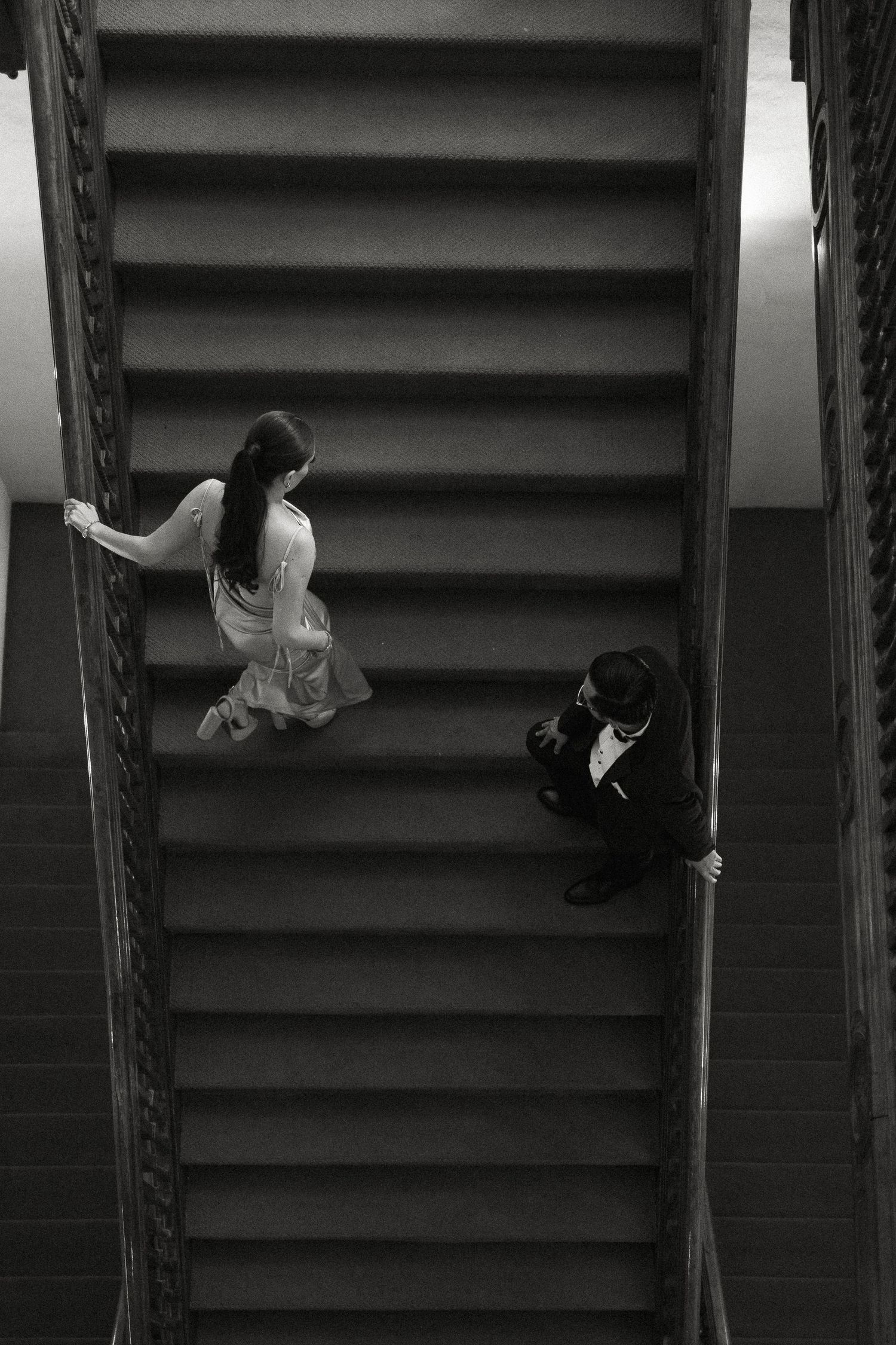 A sequence of black and white photos showing a figure climbing and posing on a staircase railing in an artistic way.
