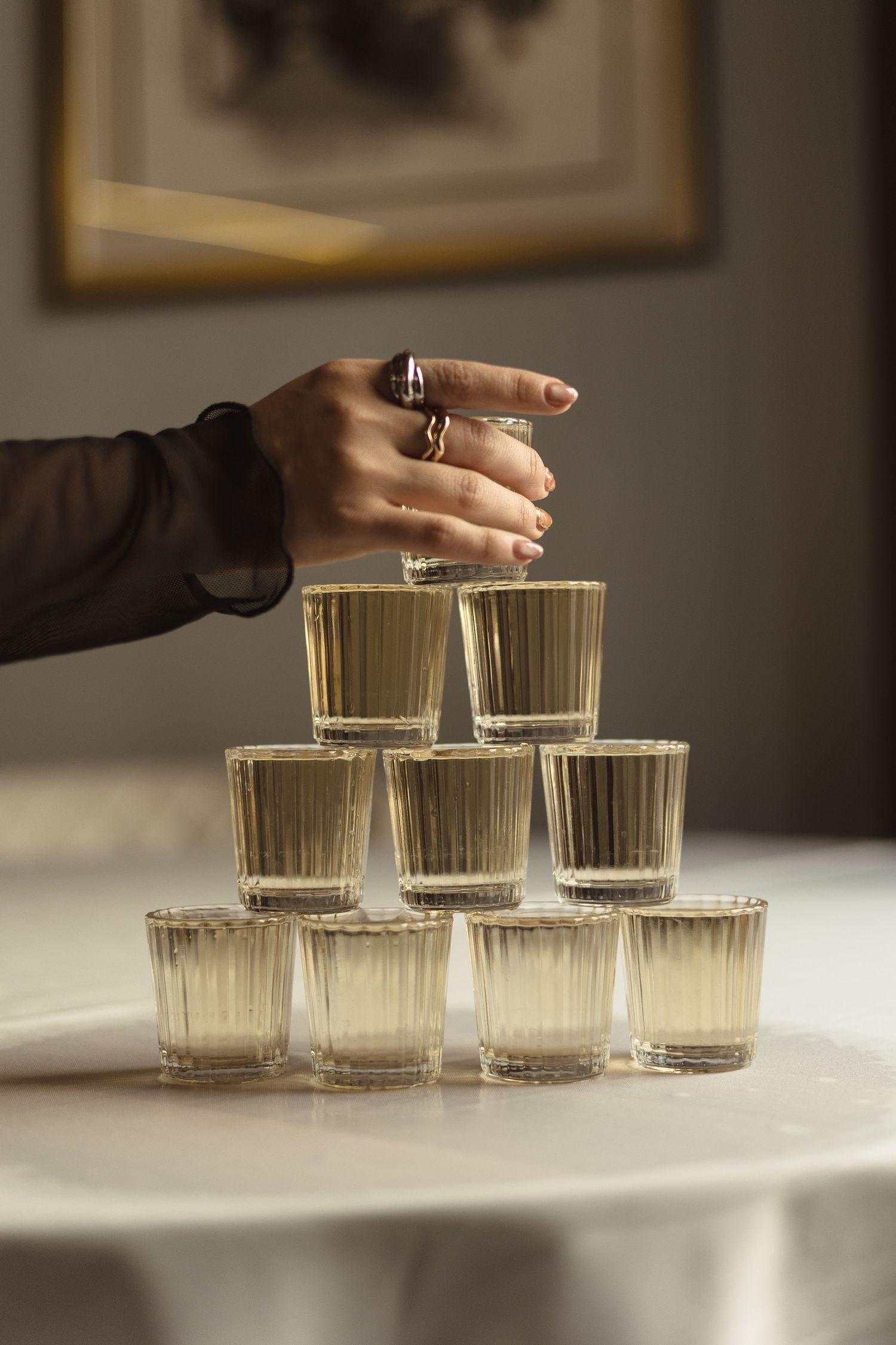 A sequence of three photos showing glass tumblers being arranged in ascending rows on a white surface.