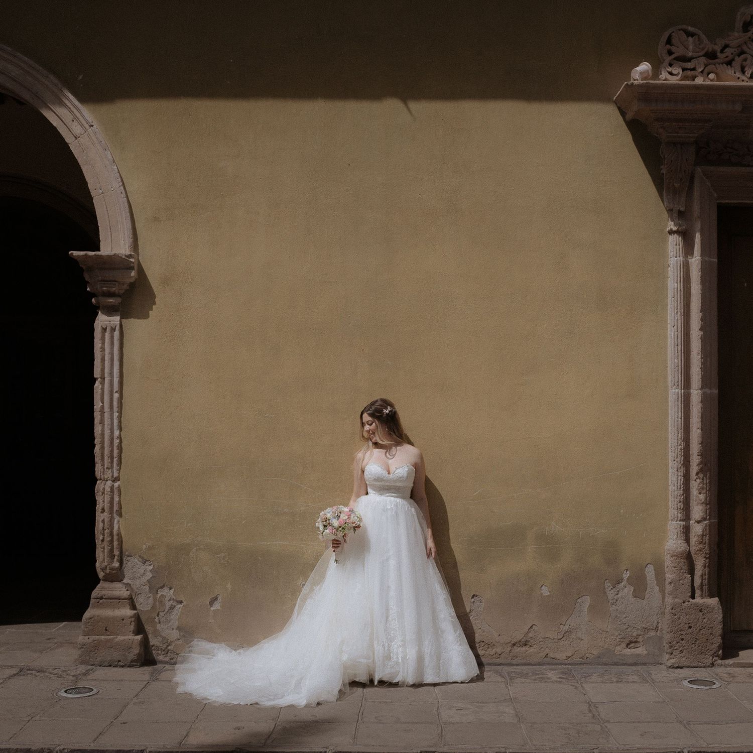 Artistic wedding photos against a neutral stone wall showing flowing white dress details.
