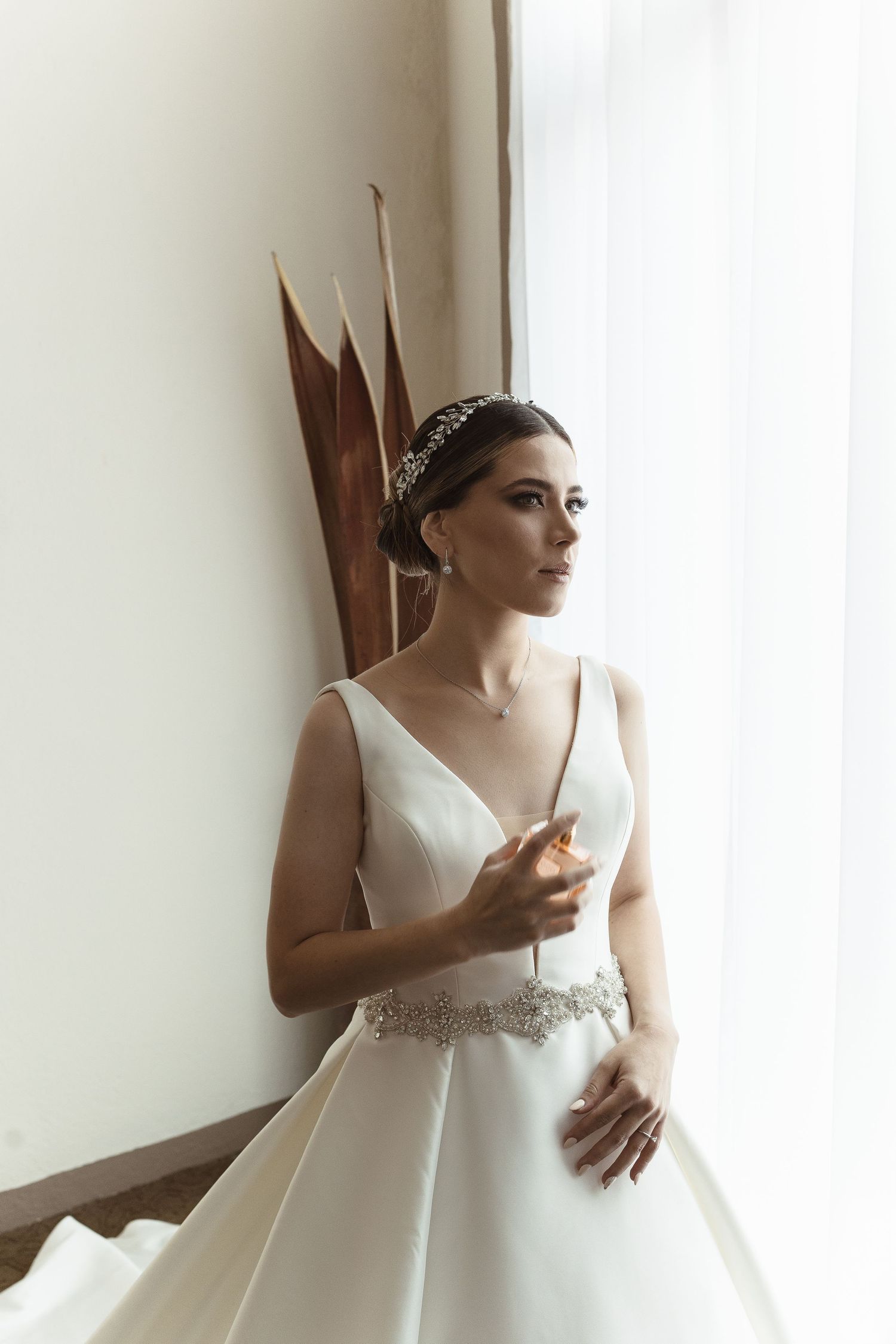 Elegant white wedding dress with a fitted bodice and flowing skirt captured in natural window light.