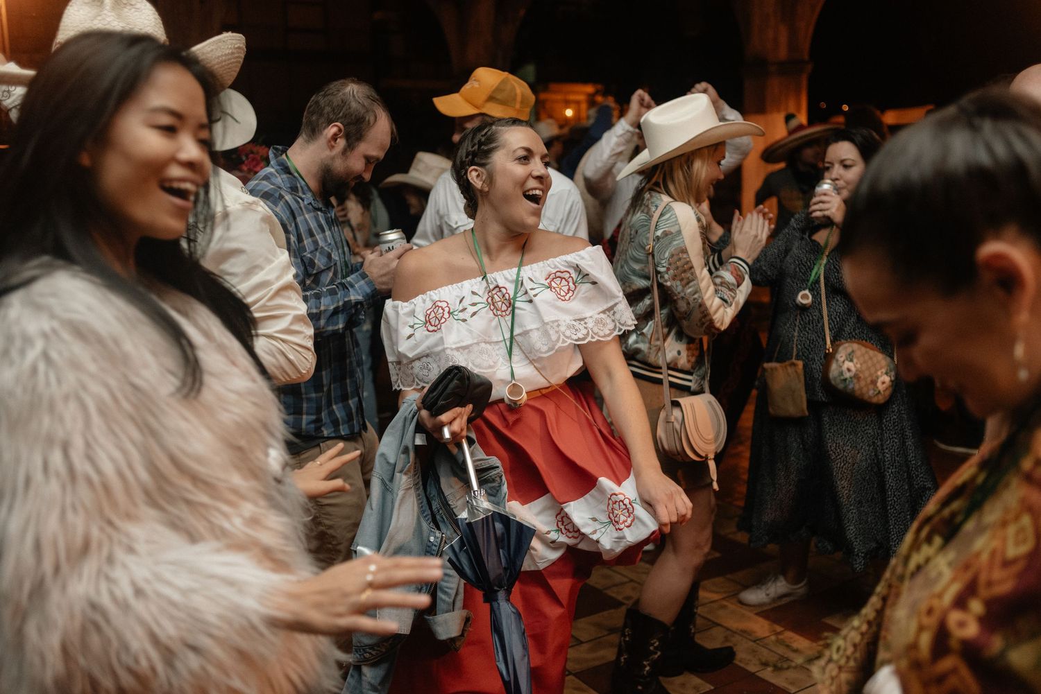 People energetically dancing and celebrating at a lively party in warm atmospheric lighting.