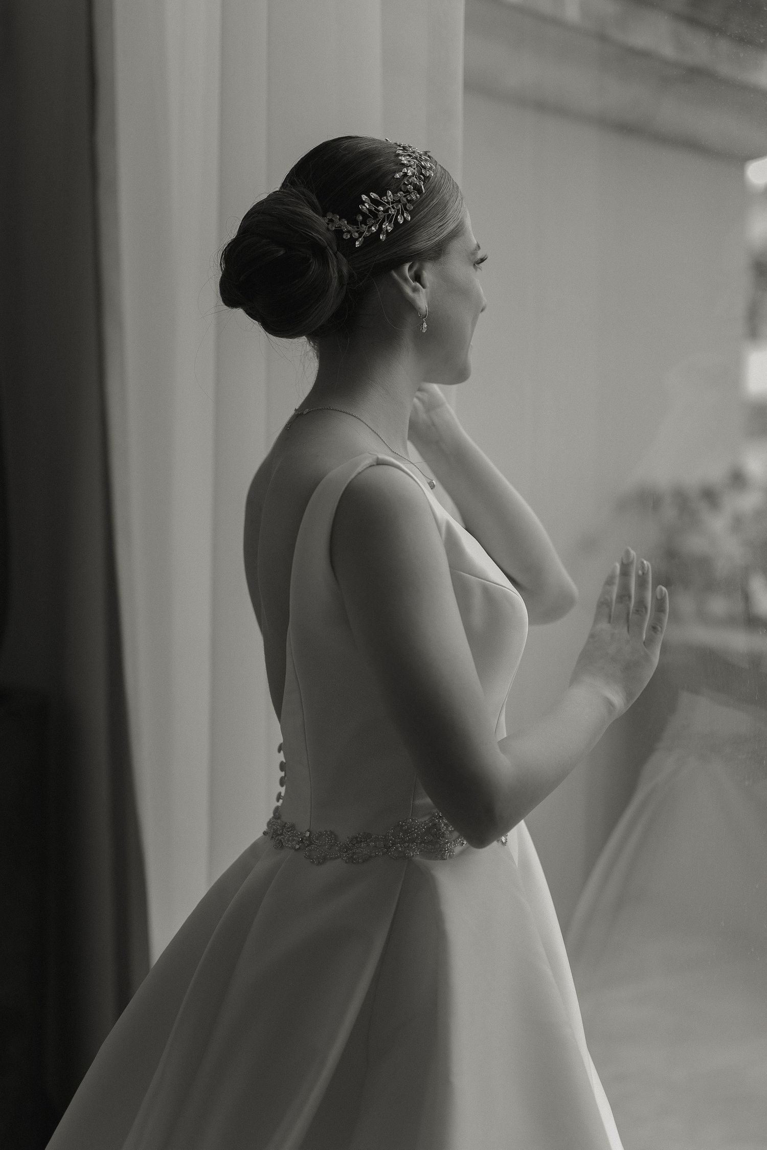 A series of black and white photos showing a bride in a flowing white gown gazing through a window.