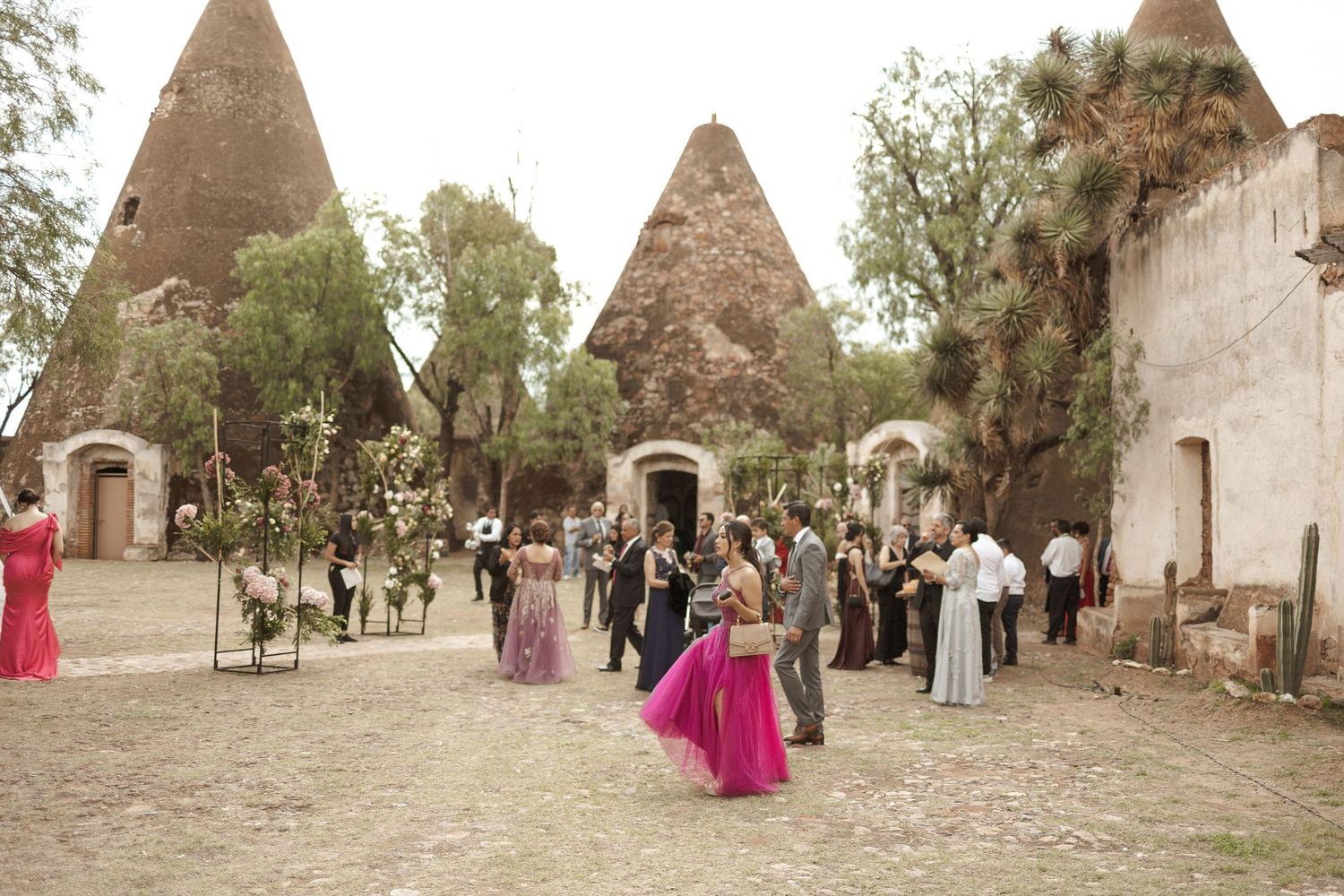 Traditional beehive-shaped stone buildings with conical roofs line a rustic pathway in an ancient village setting.